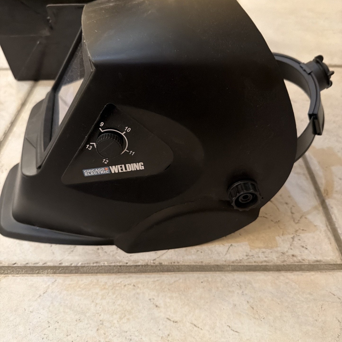Chicago Electric black auto-darkening welding helmet with adjustable shade control dial and headgear strap