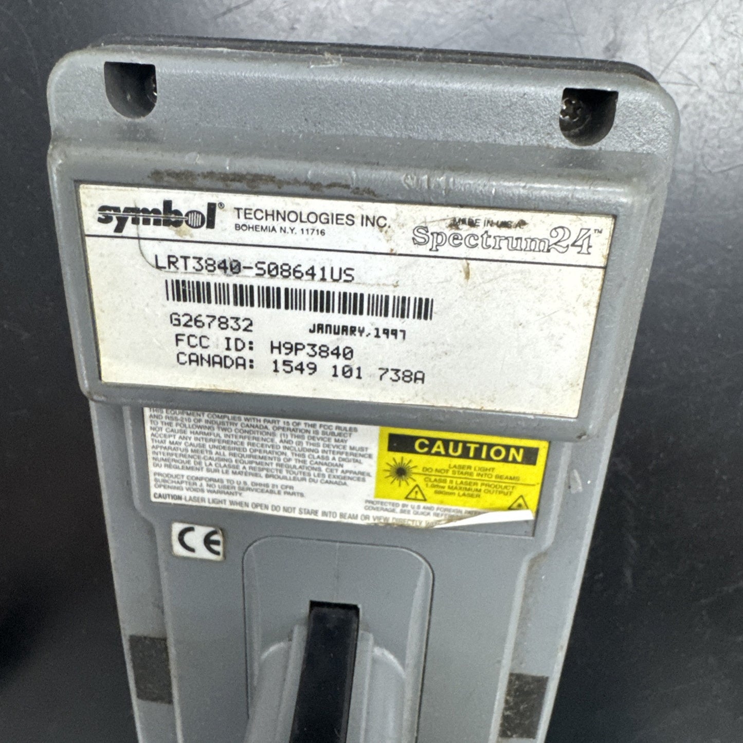 Close-up of Symbol Technologies Spectrum 24 barcode scanner label with model LRT3840 and caution warning sticker on back panel
