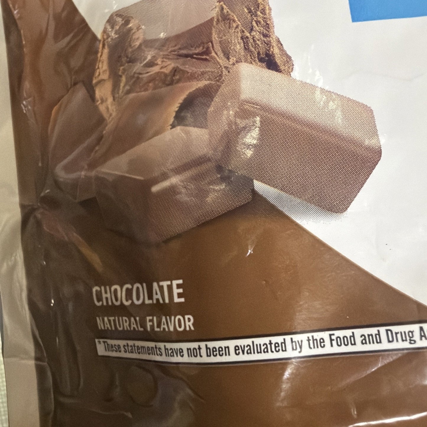 Close-up of packaging showing chocolate flavor label with natural flavor text and a compliance disclaimer at the bottom, featuring images of milk chocolate pieces on a brown background.