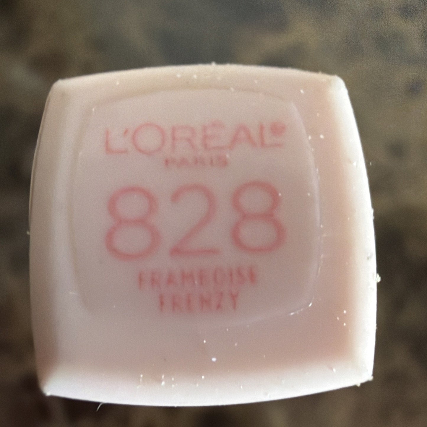 Top view of a pale pink lipstick cap featuring the L'Oréal Paris logo, shade number 828, and the name "Francoise Frenzy" printed in red text.