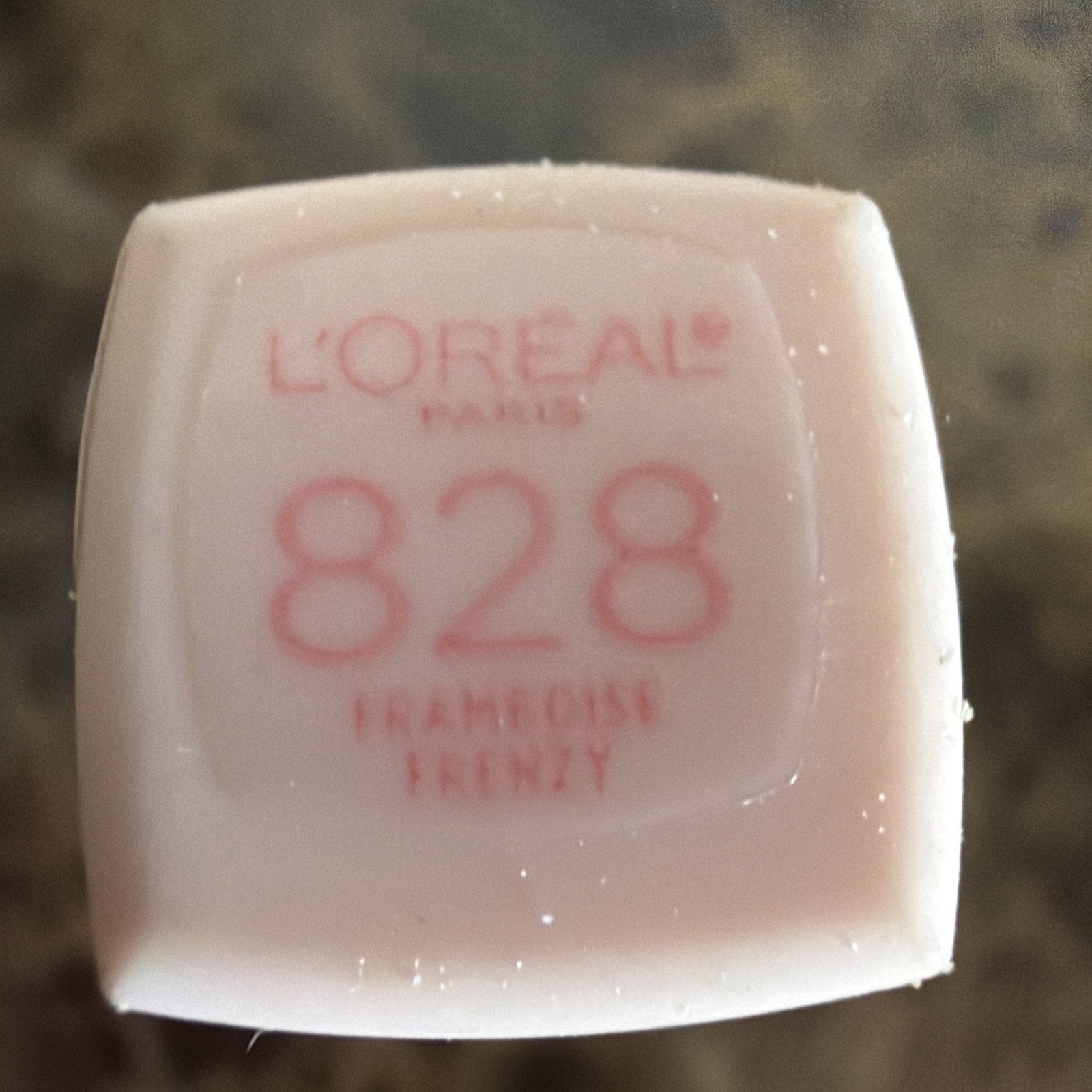 Top view of a pale pink lipstick cap featuring the L'Oréal Paris logo, shade number 828, and the name "Francoise Frenzy" printed in red text.
