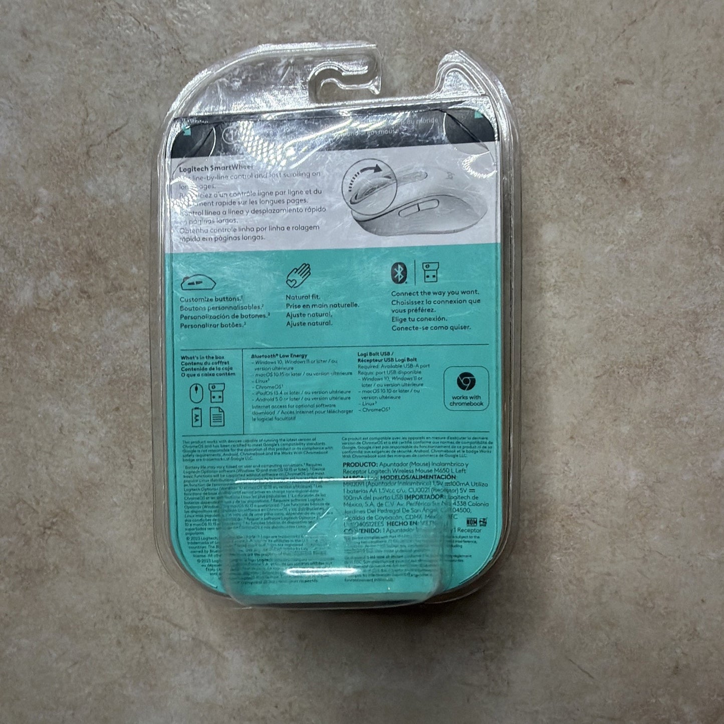 Back view of a packaged wireless computer mouse showing product features in multiple languages, including Bluetooth connectivity, smart wheel, and use instructions, with icons and regulatory text on a turquoise background.
