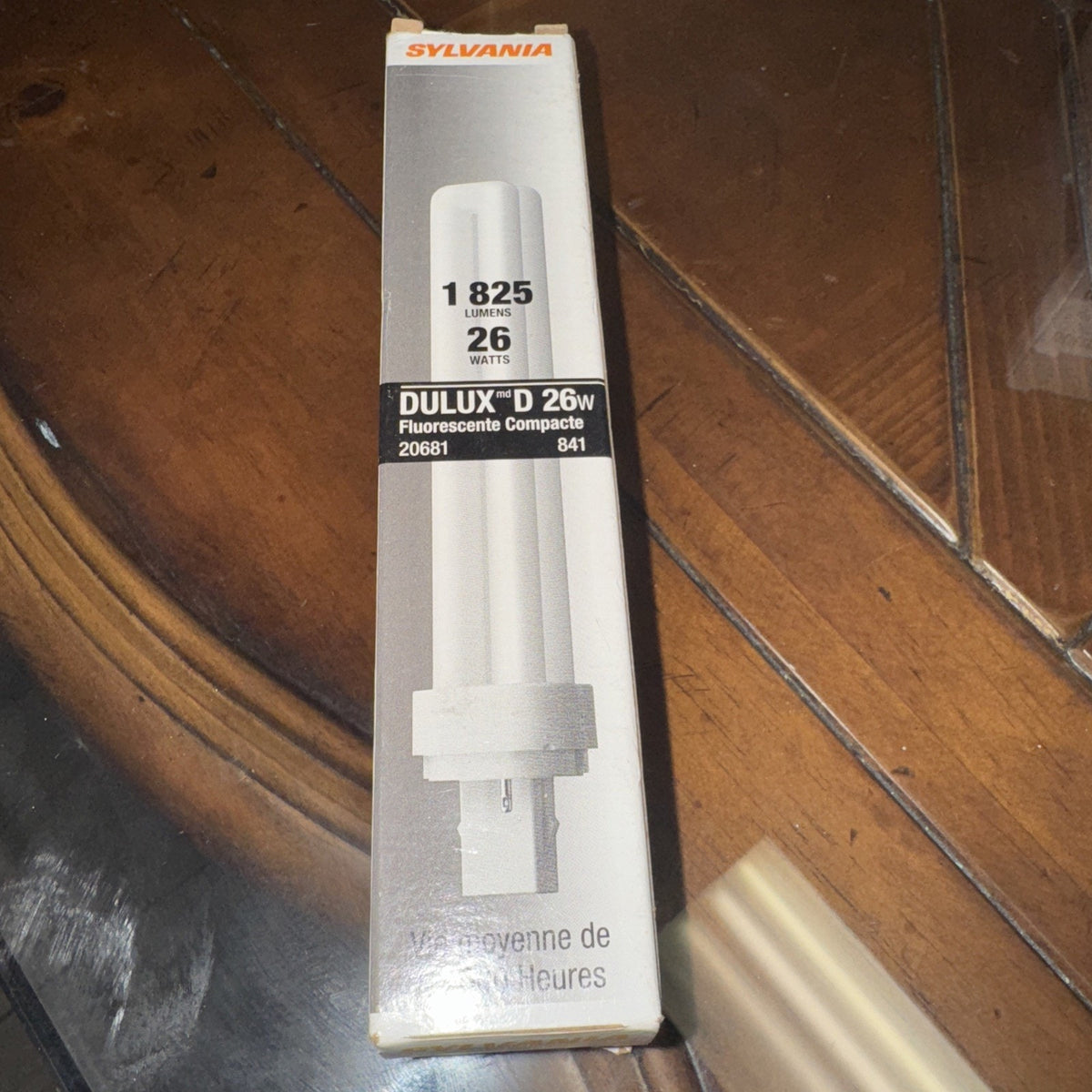 Sylvania 26W 4100K G24D-3 compact fluorescent light bulb in white packaging with product details on table surface