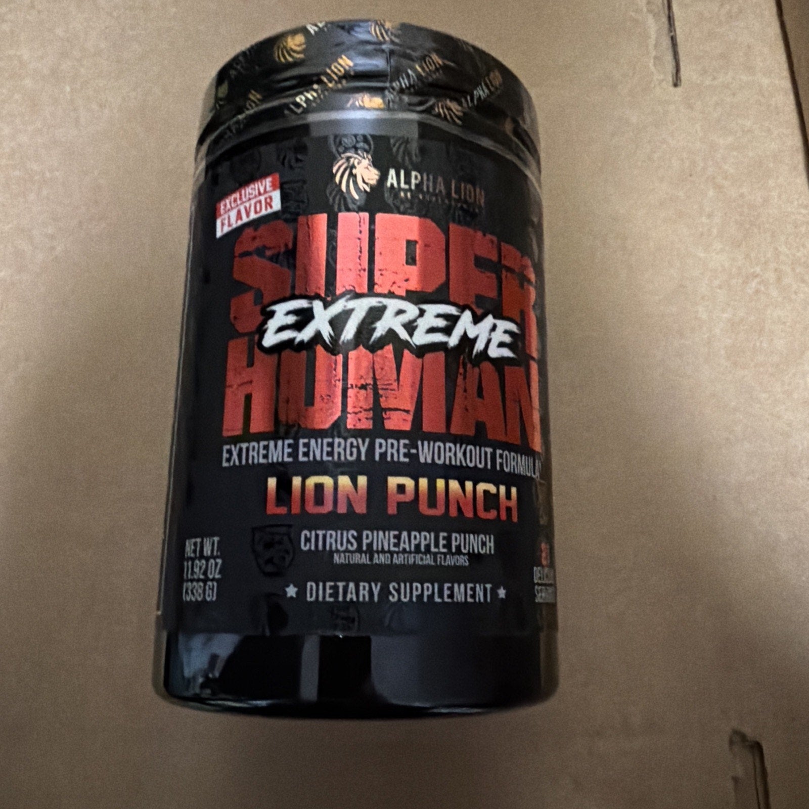 Black plastic container of Alpha Lion Super Human Extreme pre-workout supplement in Lion Punch flavor, featuring bold red and white text with citrus pineapple punch description.