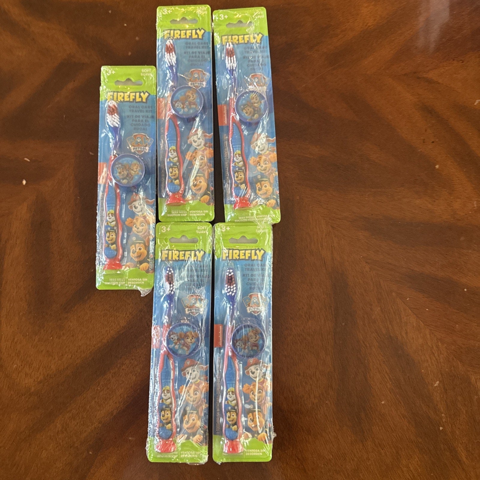 10-pack Firefly Nickelodeon Paw Patrol kids manual soft toothbrushes with caps in original packaging on wooden surface