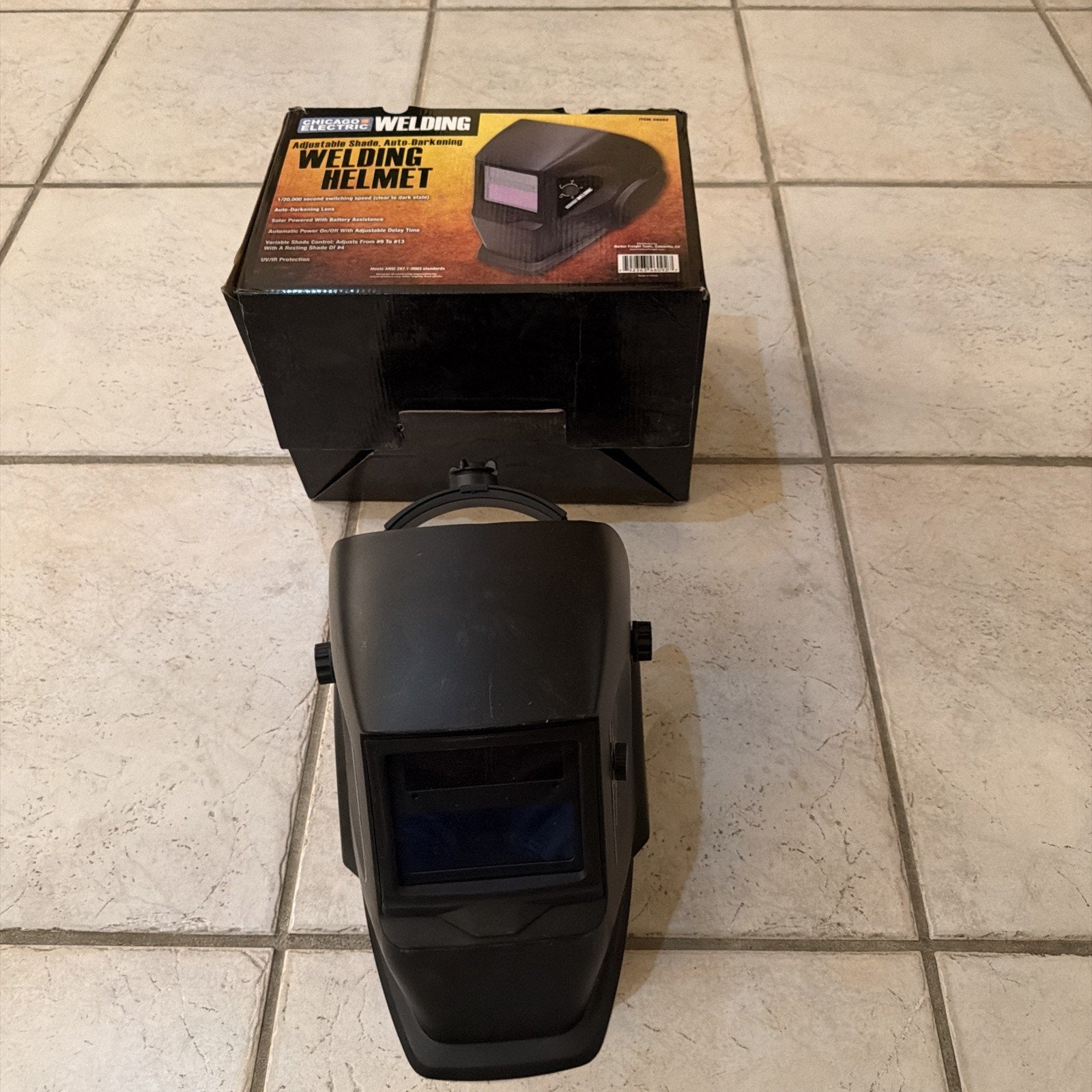 Chicago Electric auto-darkening welding helmet in black with adjustable shade and protective plastic lens shown with packaging box