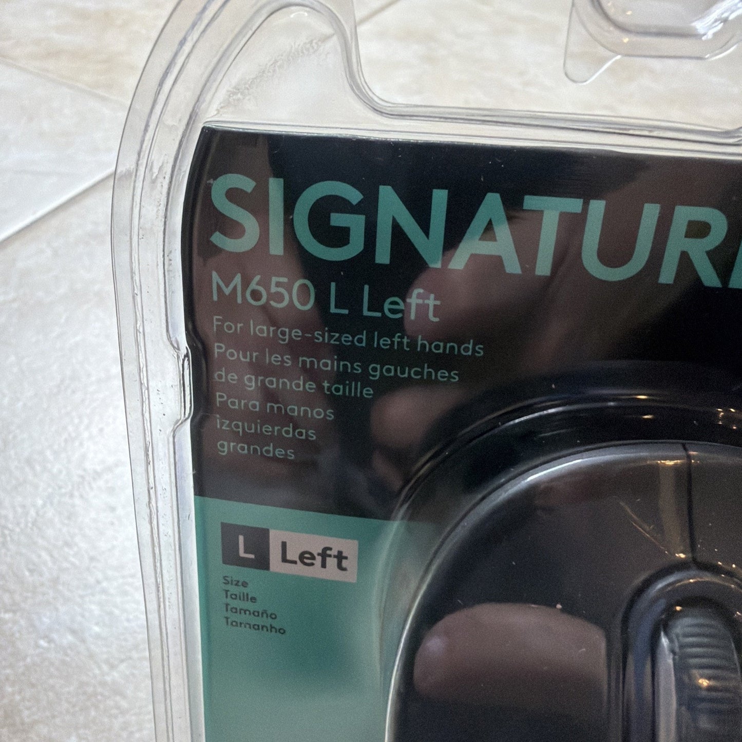 Close-up of packaging for a left-handed large-sized product labeled "Signature M650 L Left" with text in English, French, and Spanish, encased in clear plastic.