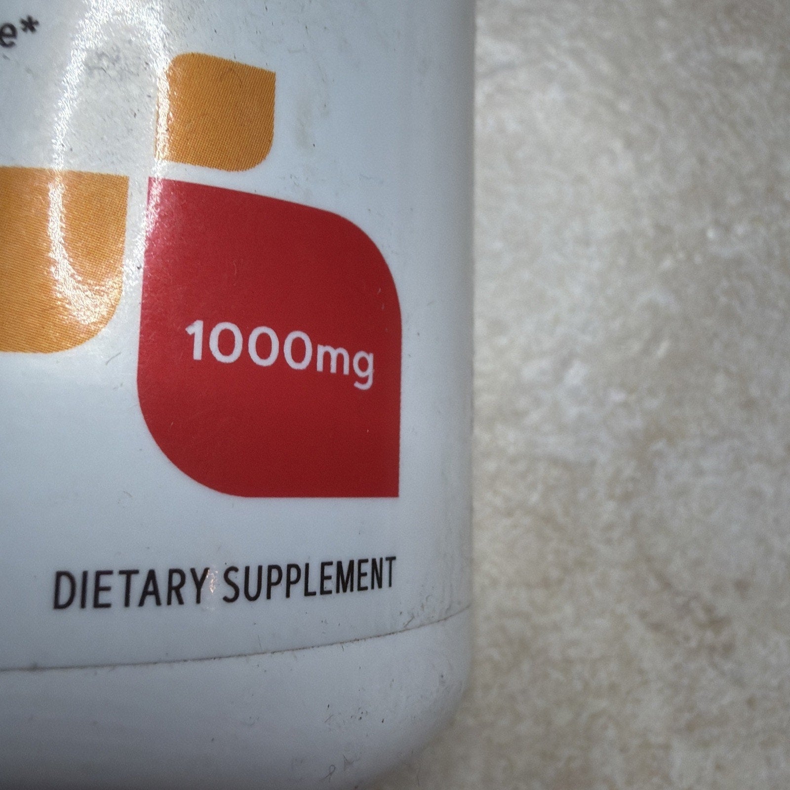 Close-up of a dietary supplement bottle label showing a red shape with "1000mg" dosage information against a textured light background.