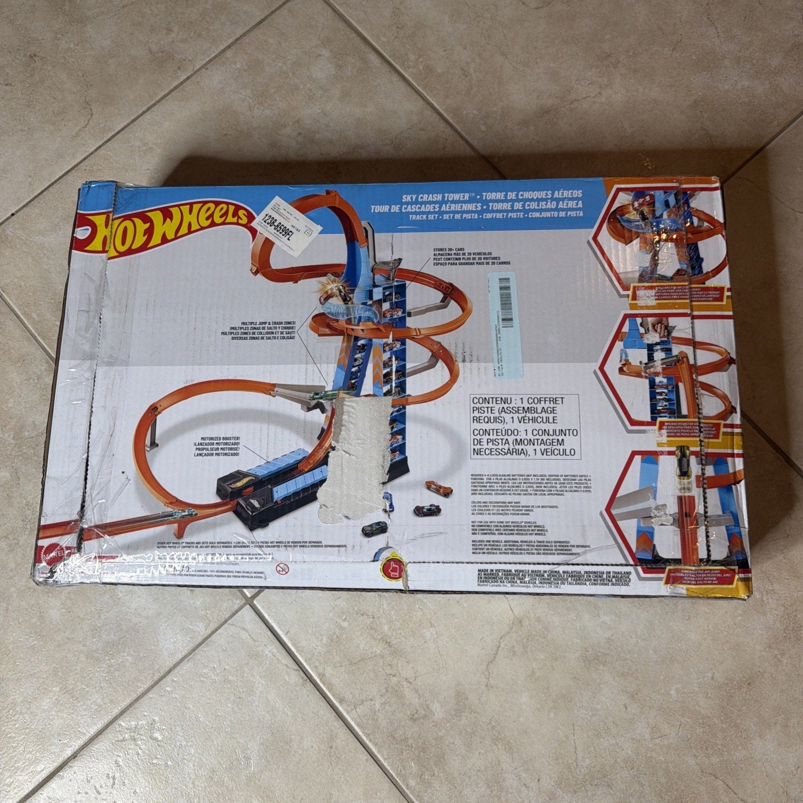 Box displaying a Hot Wheels DIY Crash Tower playset with a blue and orange spiral racetrack and two toy cars, including assembly instructions and product details on the packaging.