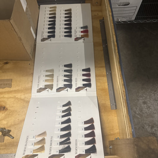 Goldwell Nectaya Color Chart Catalogue showing various hair color shades including warm blondes, cool blondes, and reds on wooden table