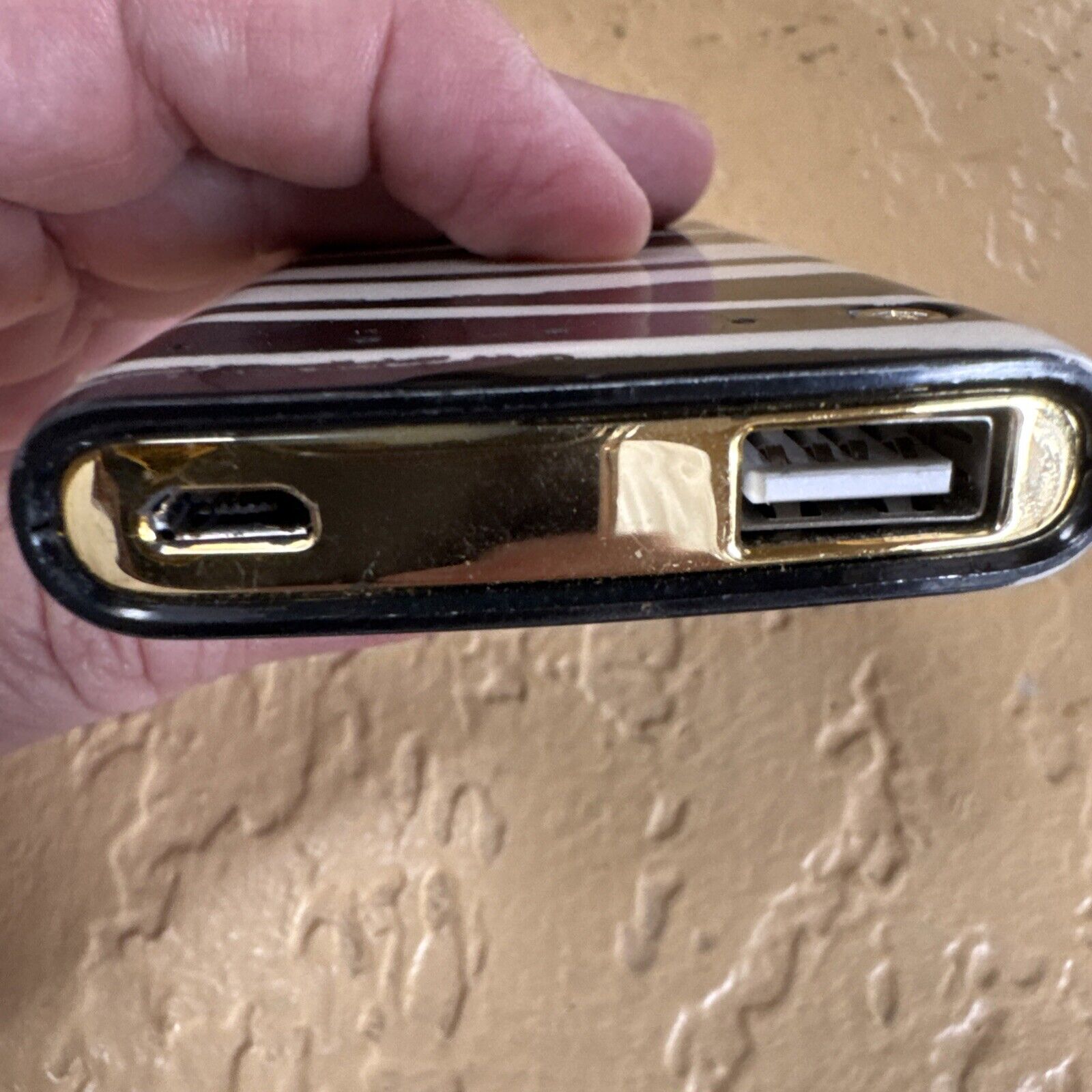 Kate Spade New York backup battery bank with striped design showing USB and charging port close-up
