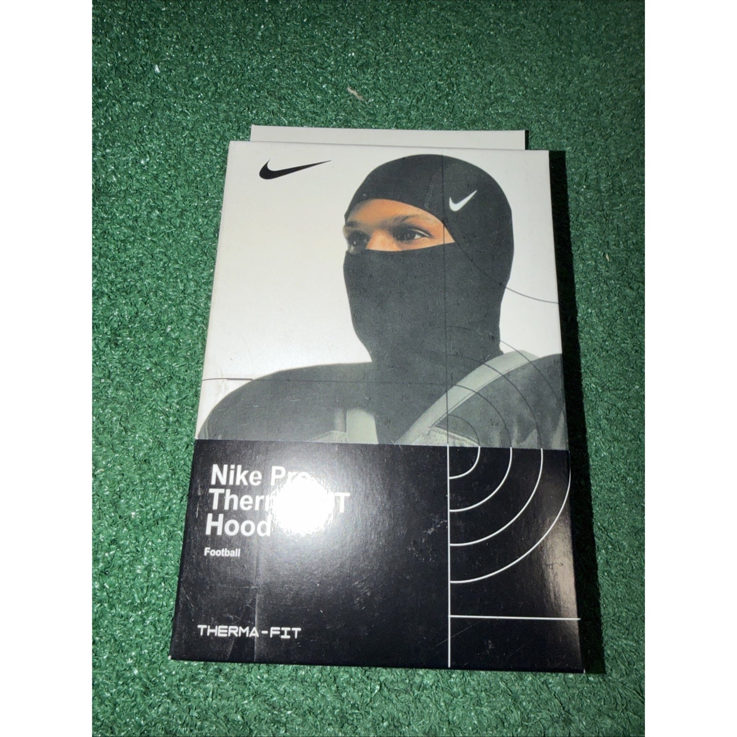 Box packaging for a Nike Pro Therma-FIT Hood designed for football, featuring an image of a person wearing the black hood with the Nike swoosh visible on the forehead area.