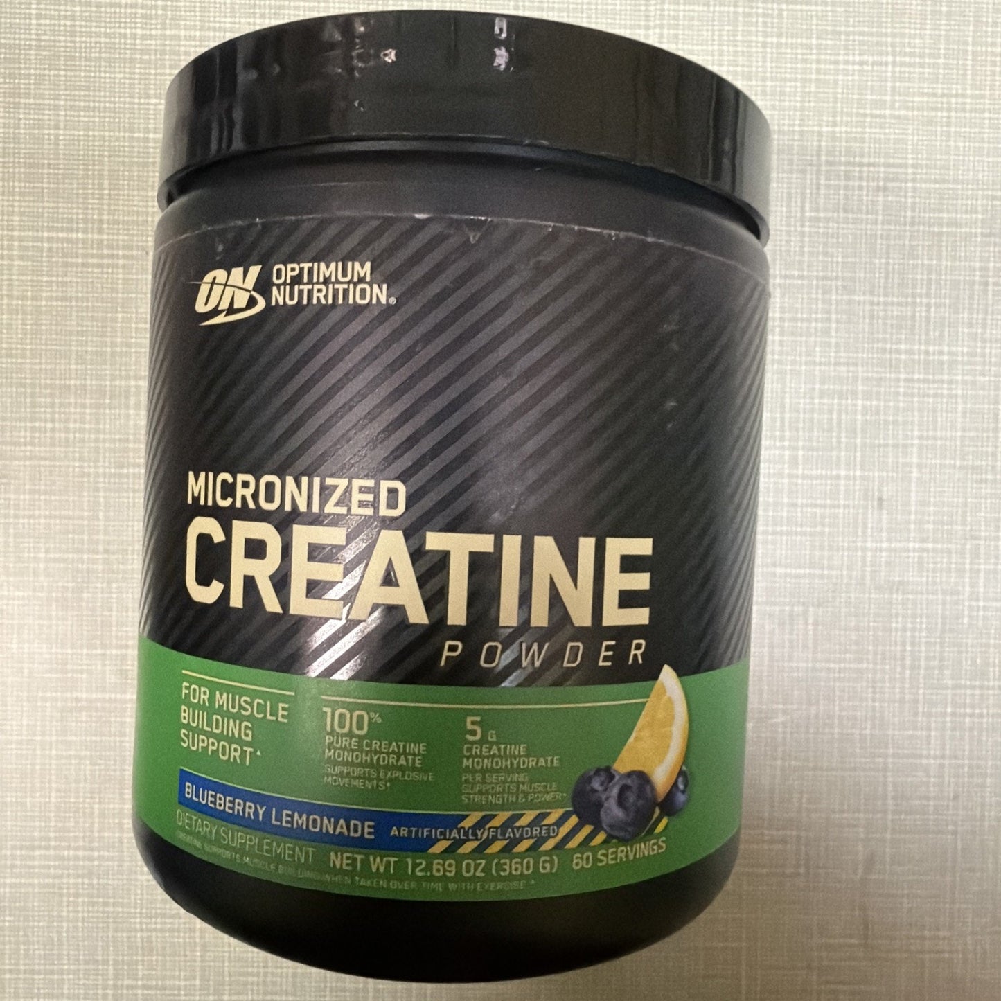 Black container of Optimum Nutrition Micronized Creatine Powder in blueberry lemonade flavor, featuring 100% pure creatine monohydrate with 60 servings for muscle building support.