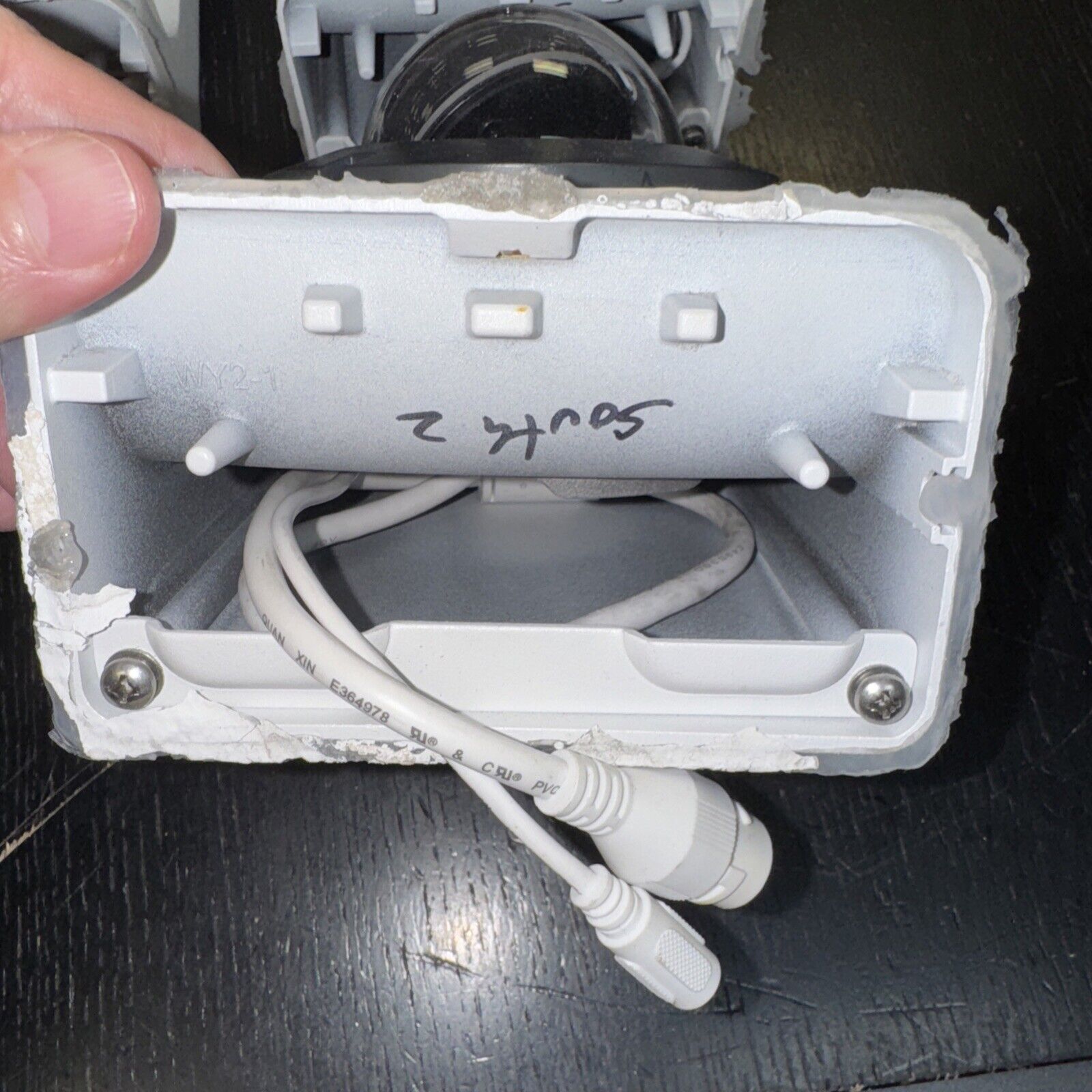 Lot of three Alarm.com surveillance cameras with bases showing cables and mounting details inside housing box