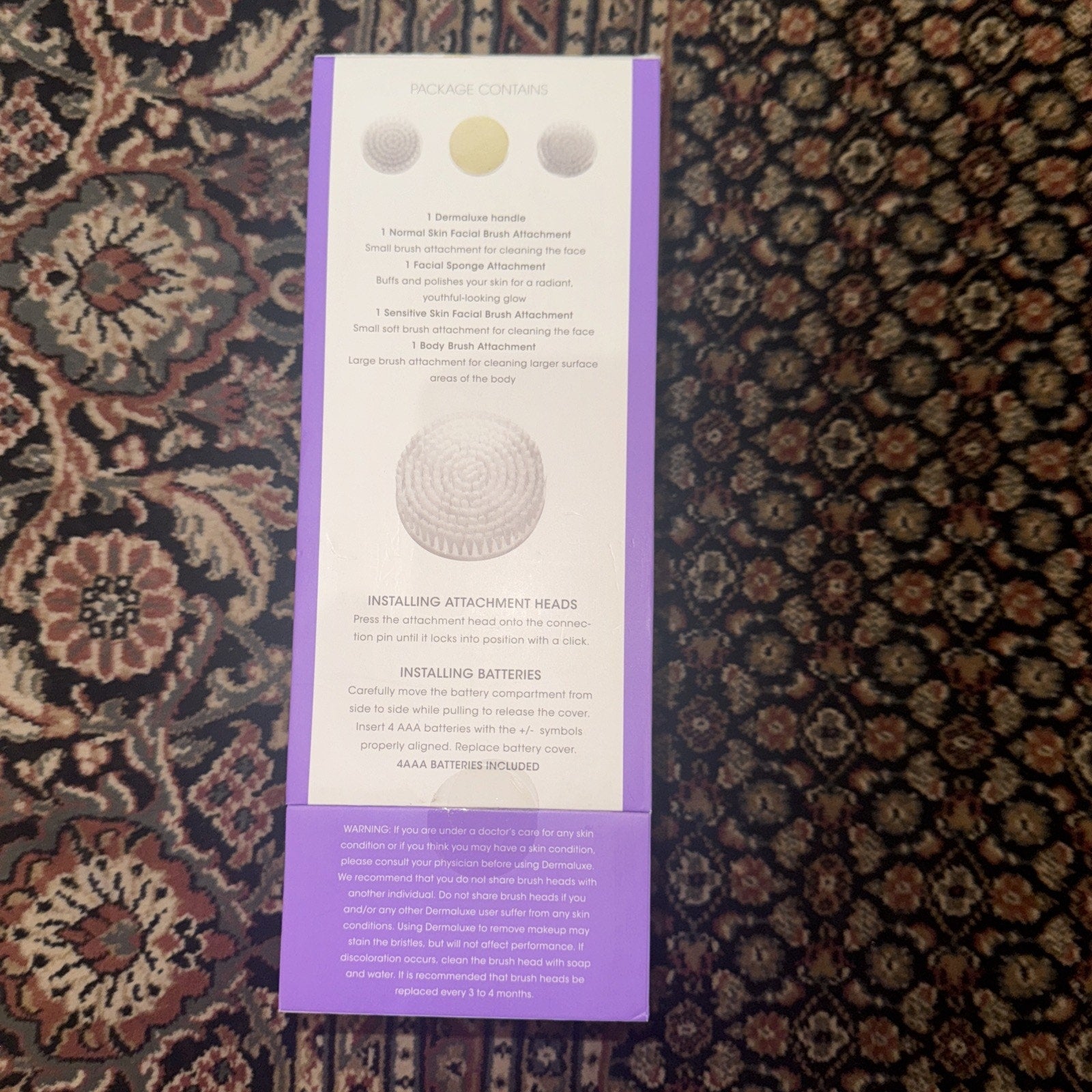 DERMALUXE Advance Cleansing System packaging showing included brush attachments and battery installation instructions
