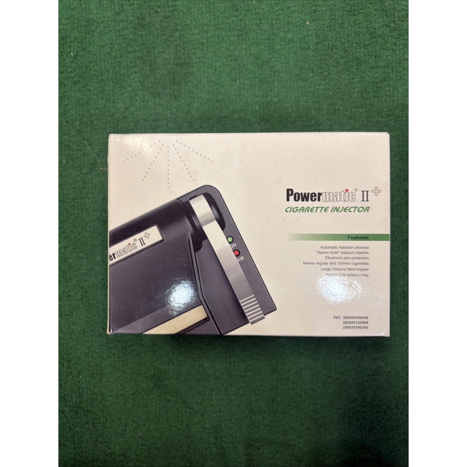 White product box with printed image of a black and beige Powermatic II cigarette injector machine, featuring small colored indicator lights and text listing product features.