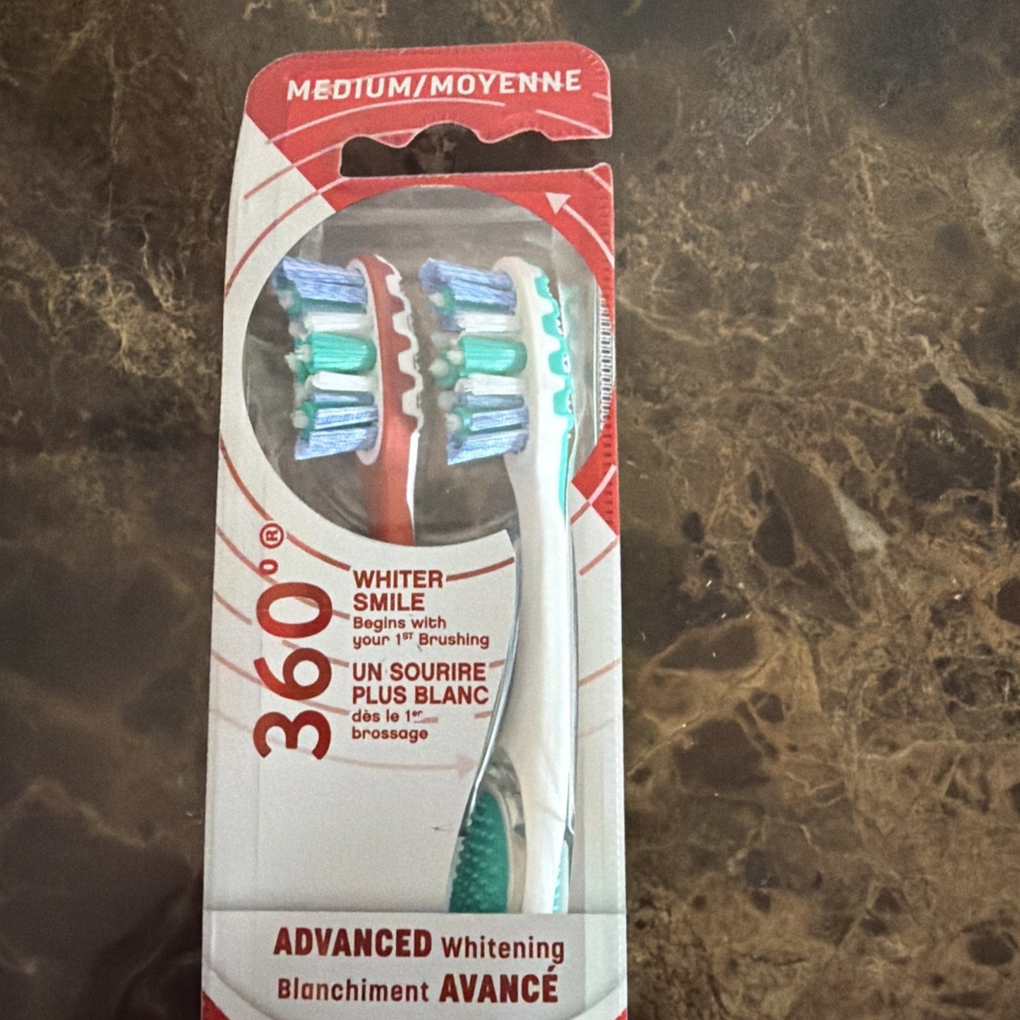 Package of two medium toothbrushes with multi-colored bristles, labeled for 360-degree advanced whitening and featuring English and French text on a white and red backing card.