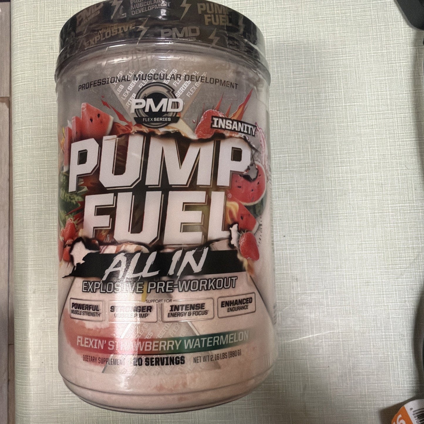 Large plastic container of Pump Fuel All In pre-workout powder with strawberry watermelon flavor, featuring branding and benefits like intense energy, muscle pump, and endurance support.