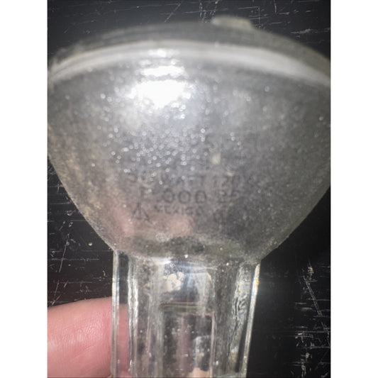 Close-up image of a clear 50PAR20/H/FL 120V 50W replacement light bulb held by a hand against dark background