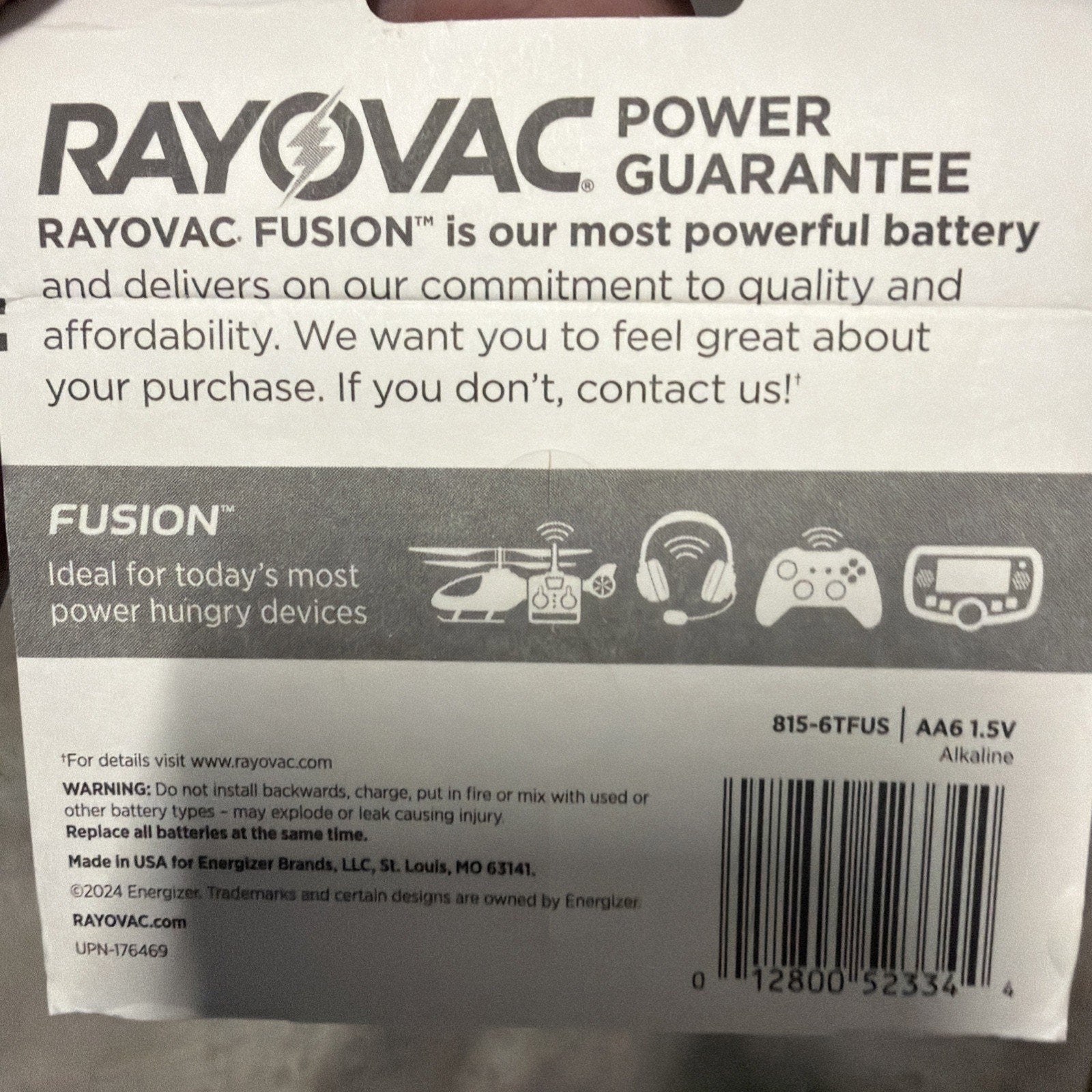 Packaging label for Rayovac Fusion alkaline AA batteries highlighting power guarantee, suitability for high-drain devices, barcode, and safety warnings on a white background.