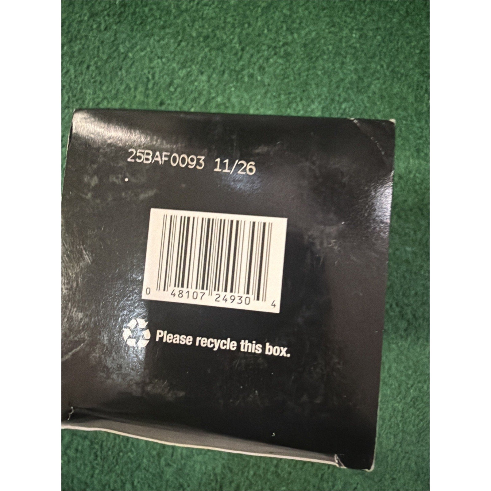 Black product box bottom showing a barcode, a recycling symbol with "Please recycle this box" text, and a printed lot number and date code "25BAF0093 11/26" on a textured green background.