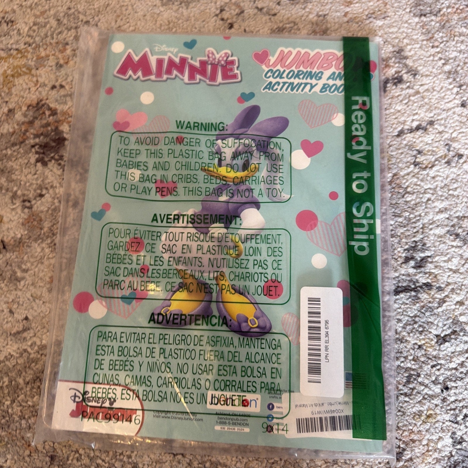 Back of a Disney Minnie Jumbo Coloring and Activity Book with warning text about plastic bag suffocation risk, sealed in clear packaging on a carpeted surface.