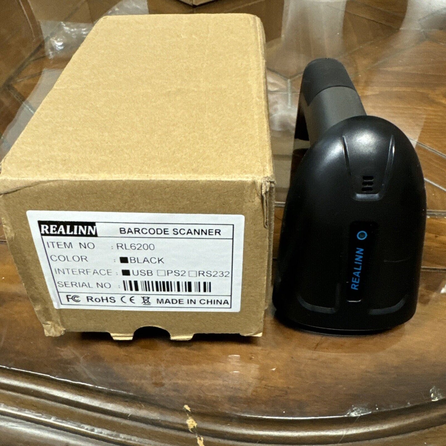 Realinn RL6200 black wireless barcode scanner next to its cardboard packaging box with product label visible
