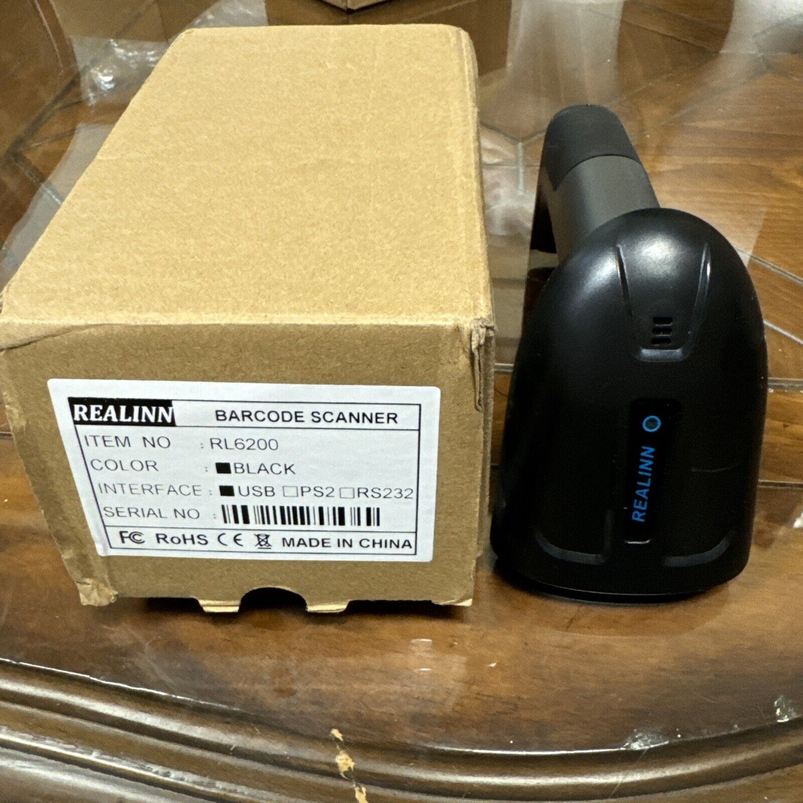 Realinn RL6200 black wireless barcode scanner next to its cardboard packaging box with product label visible