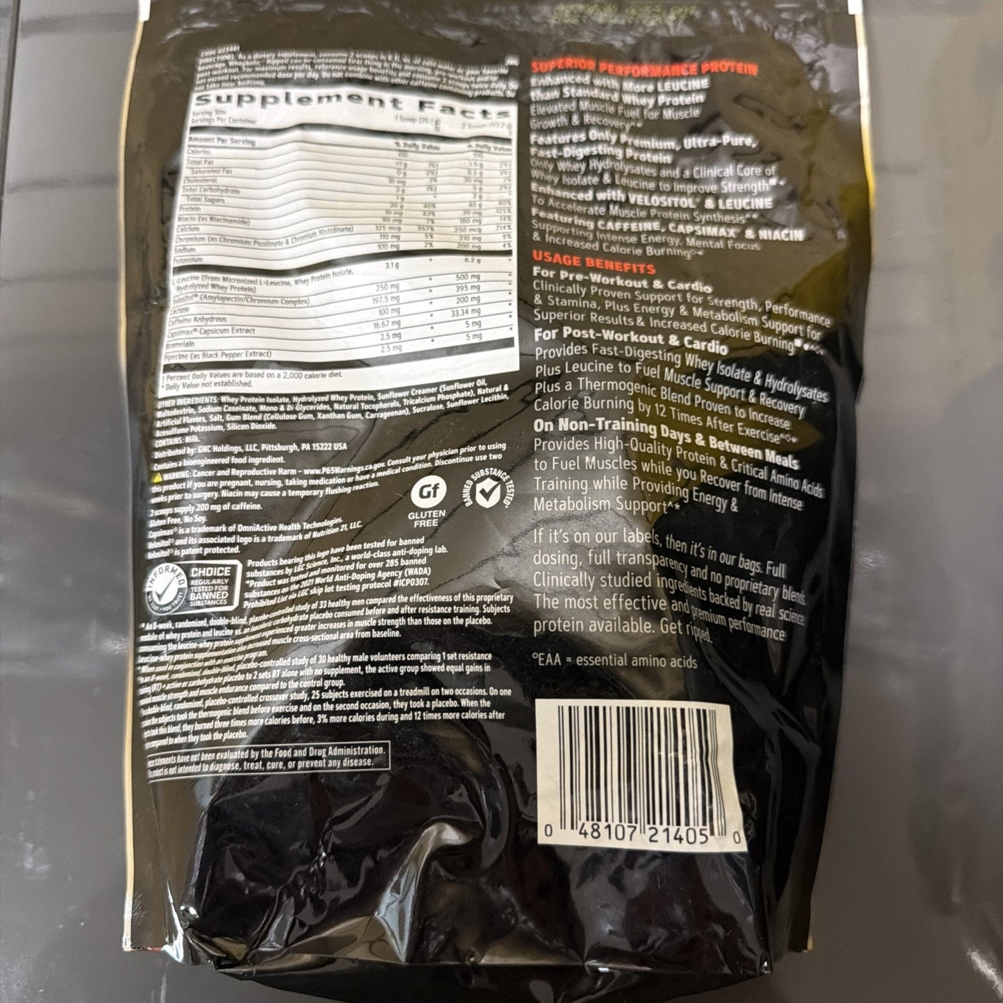 Back of a black supplement bag displaying detailed supplement facts, usage benefits for workout and recovery, ingredient list, allergen information, certification logos, barcode, and product quality statements.