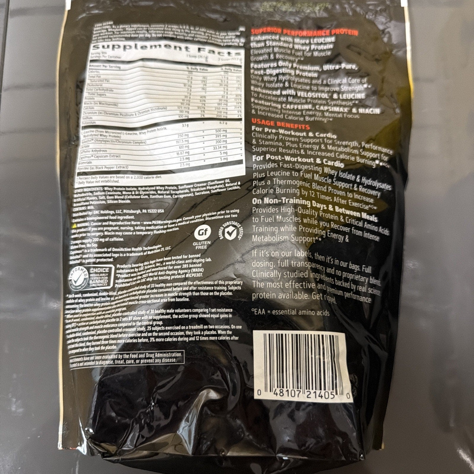 Back of a black supplement bag displaying detailed supplement facts, usage benefits for workout and recovery, ingredient list, allergen information, certification logos, barcode, and product quality statements.