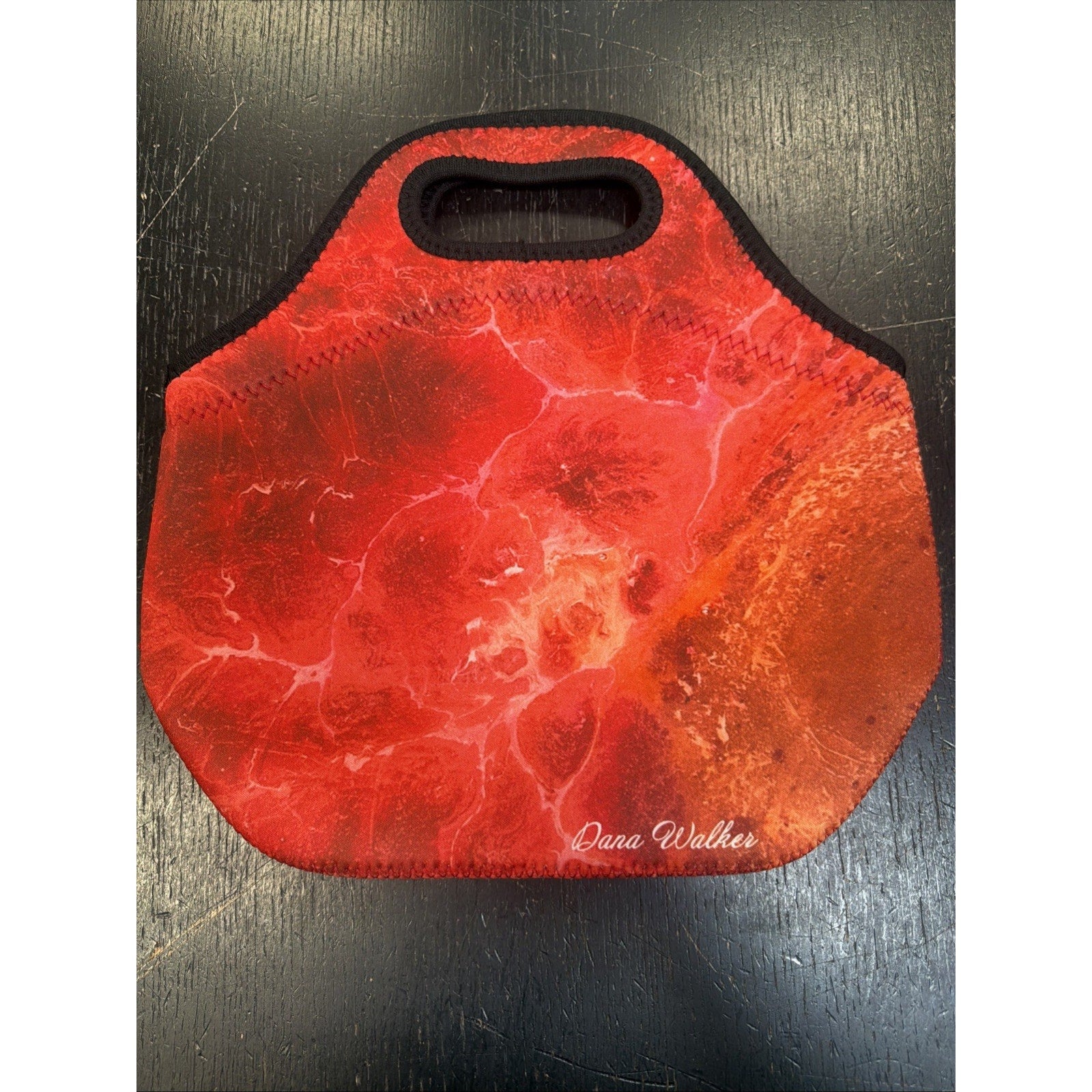 Red and orange marbled insulated lunch tote with a built-in handle and the name "Dana Walker" printed in white on the lower right corner.