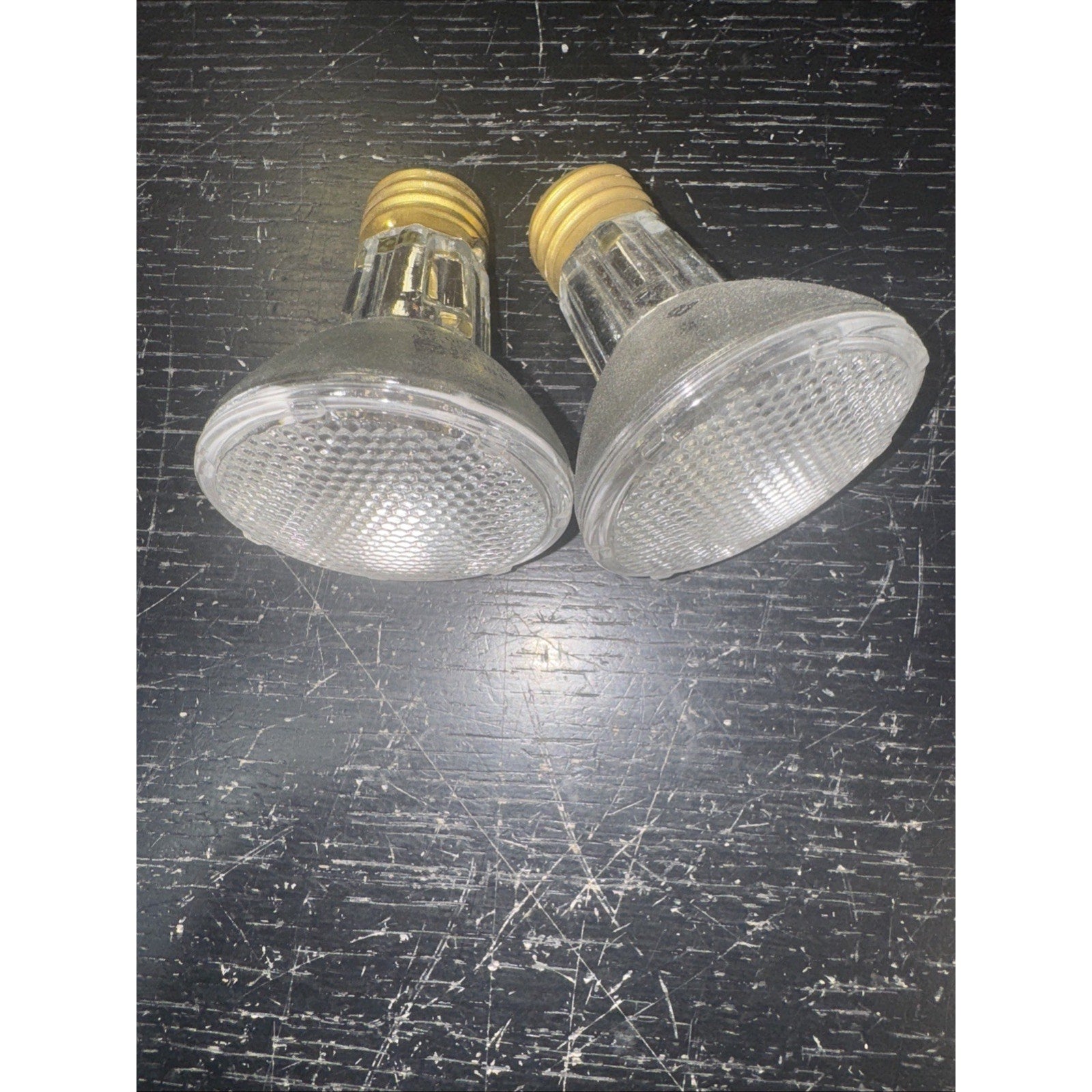Two replacement 50PAR20/H/FL 120V 50W light bulbs with clear textured glass and brass screw bases on black surface