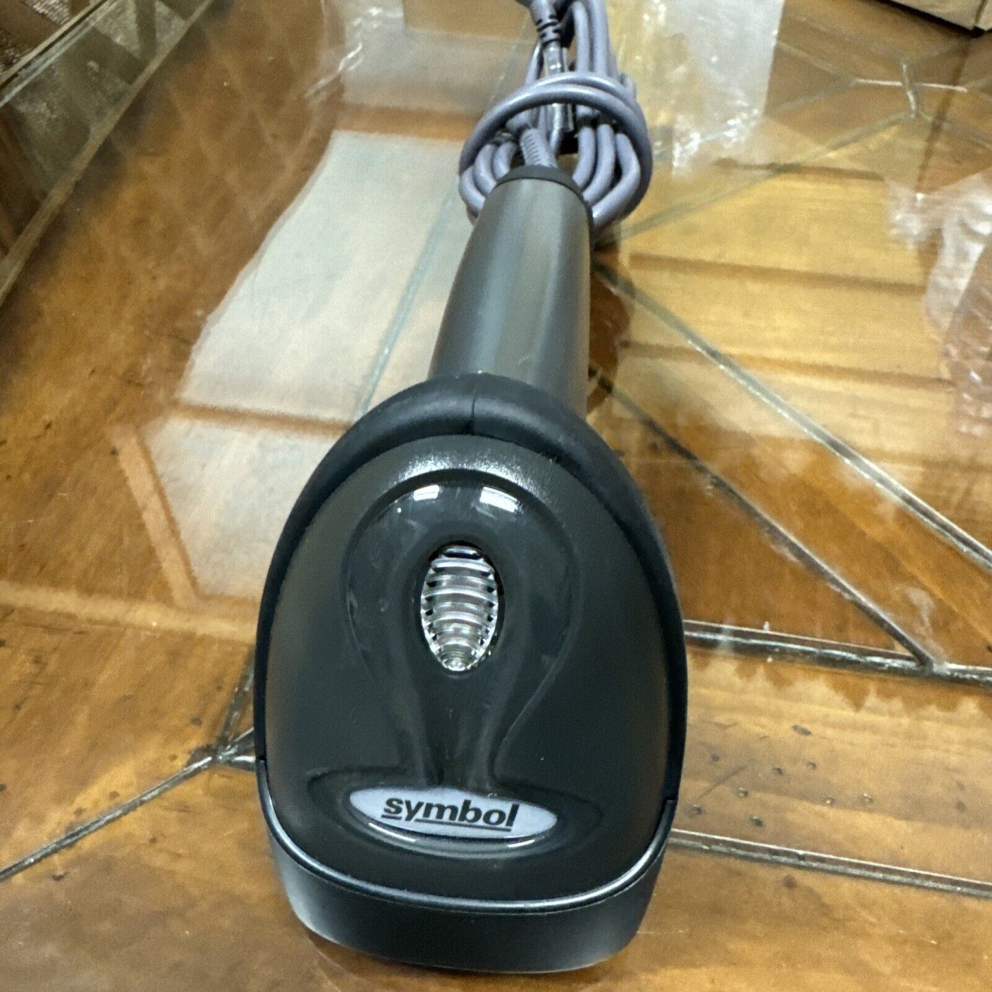 Symbol Motorola LS2208 handheld black barcode scanner with USB cable coiled on reflective surface