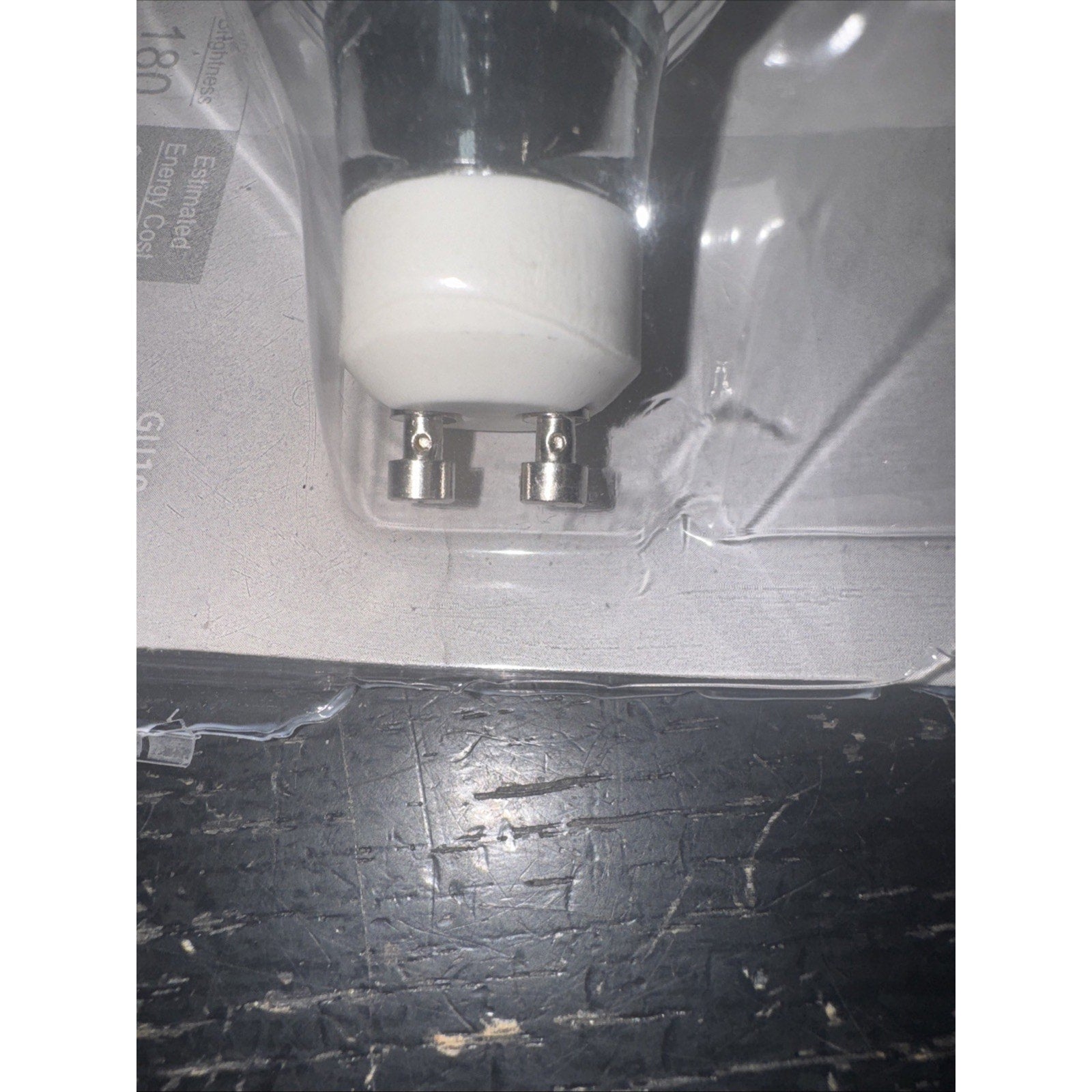 Close-up of GE 61142 GU10 35W indoor floodlight bulb with clear glass and bi-pin base in packaging