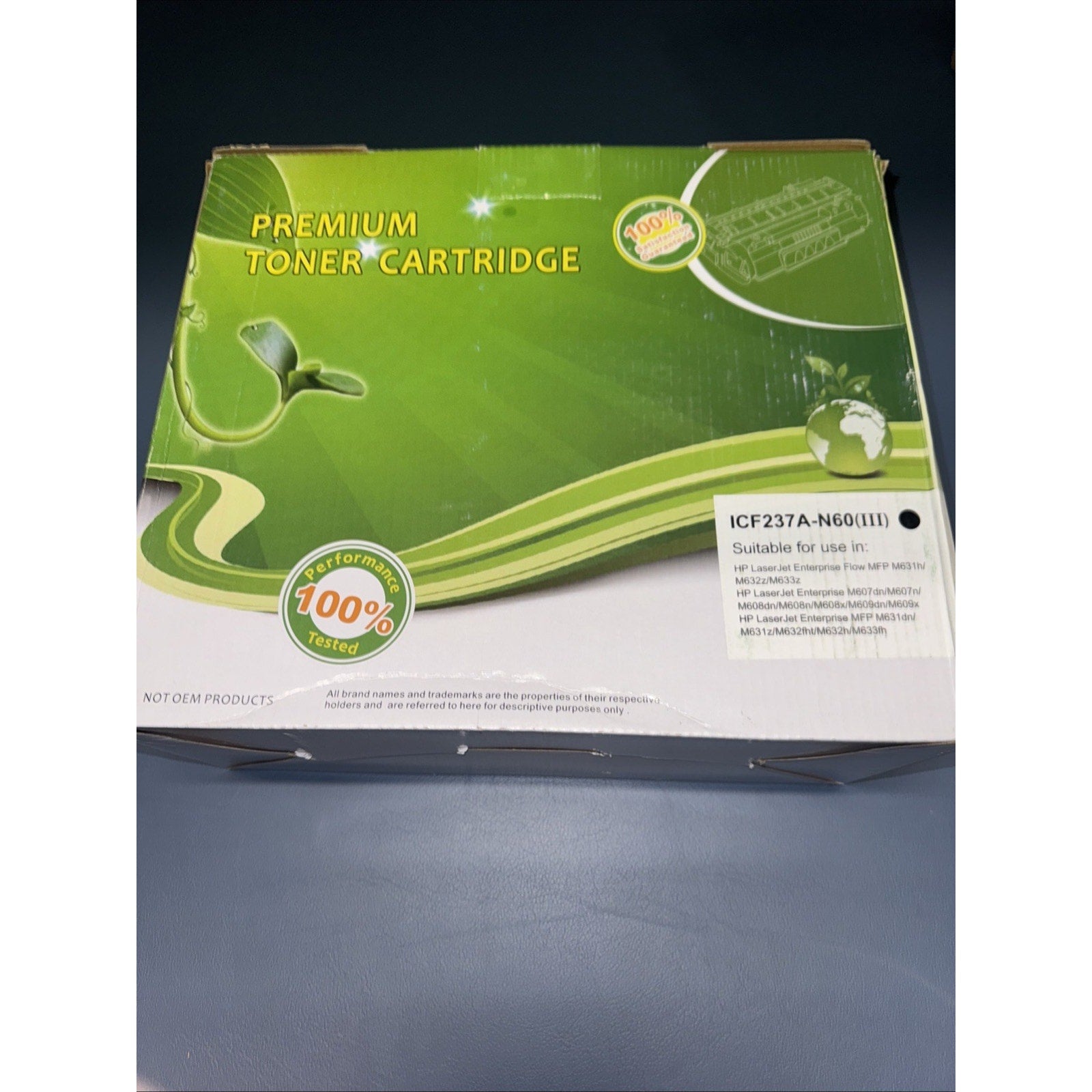 Green and white packaging box for a premium toner cartridge, featuring eco-friendly graphics with a small plant and globe illustration, and a white label listing compatible printer models.