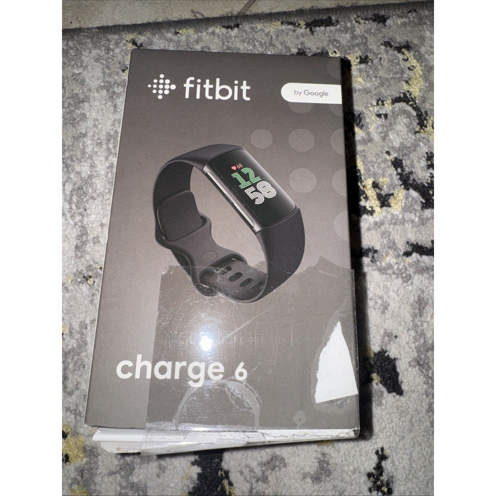 Packaging of Fitbit Charge 6 fitness tracker in black with digital display and Google branding on front box cover