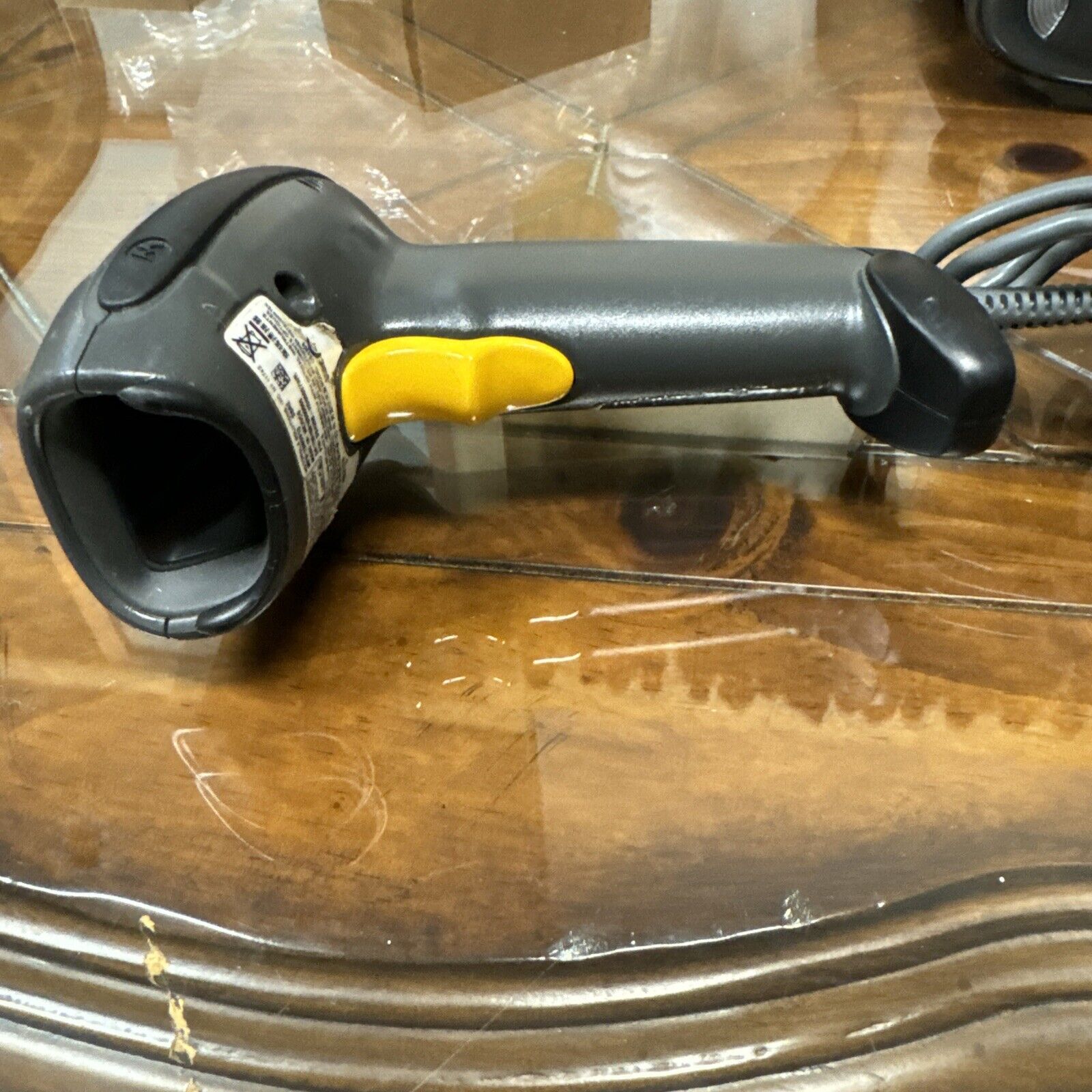 Motorola DS4208-DL0007WR barcode reader scanner with yellow trigger and wired connection on wooden surface