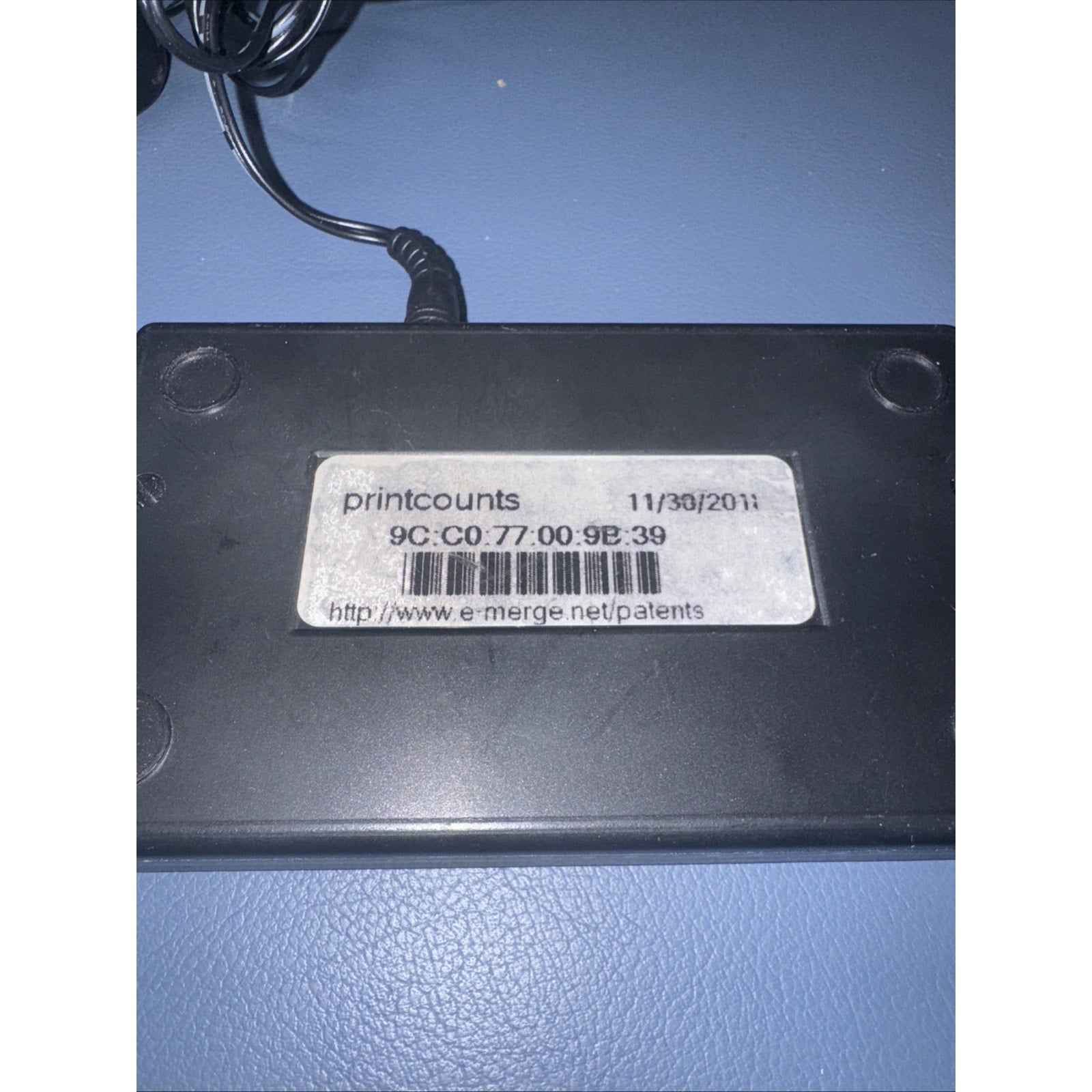 Black Print Counter DEX Imaging Emerge Print Management device with barcode and date label on blue surface