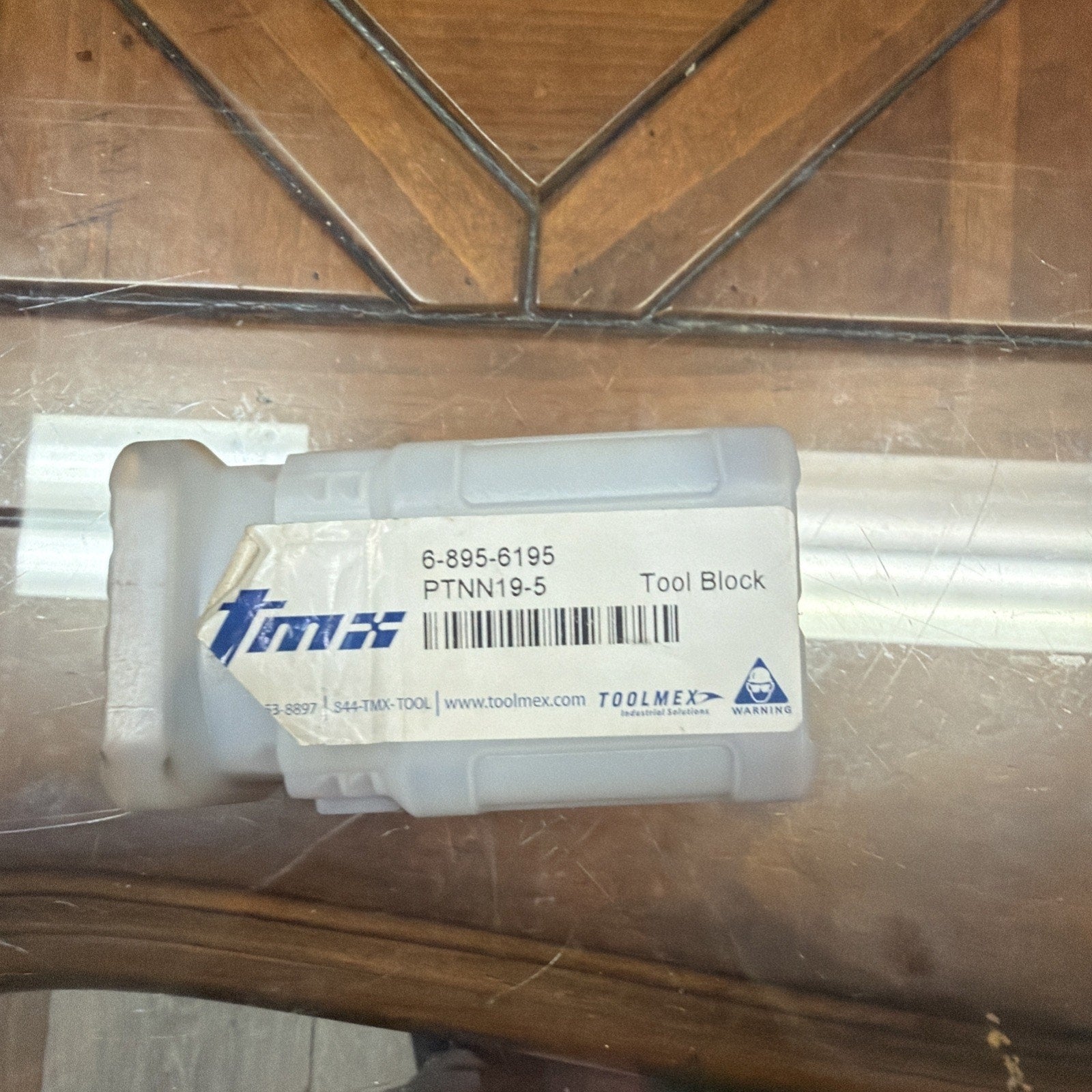 Clear plastic container with a white label displaying the product code "6-895-6195," model "PTNN19-5," the term "Tool Block," a barcode, the Toolmex logo, and a blue triangular warning symbol.
