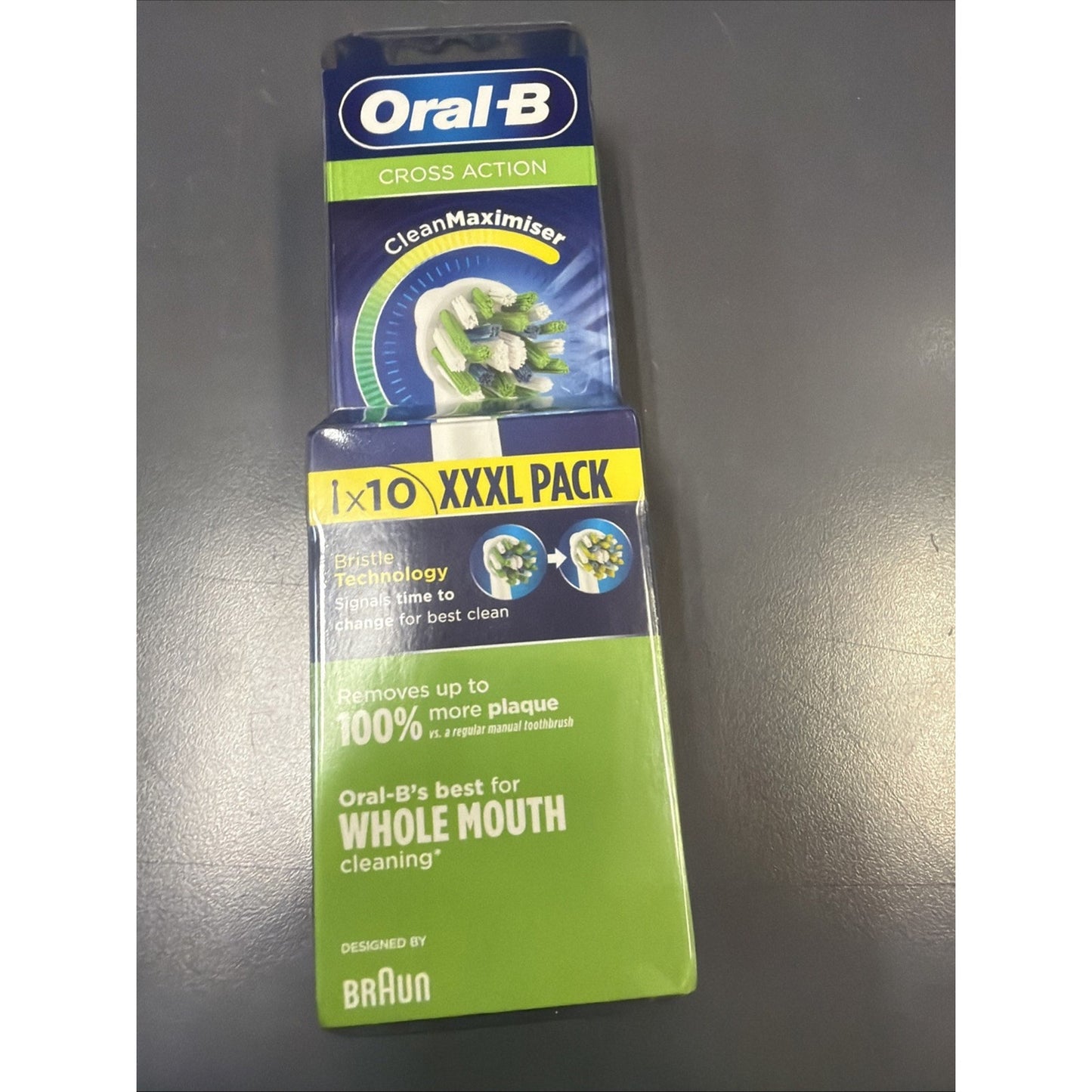 Blue and green Oral-B Cross Action toothbrush head refill package with a "CleanMaximiser" label, bristle images, and a yellow "1x10 XXXL Pack" banner on a gray surface.