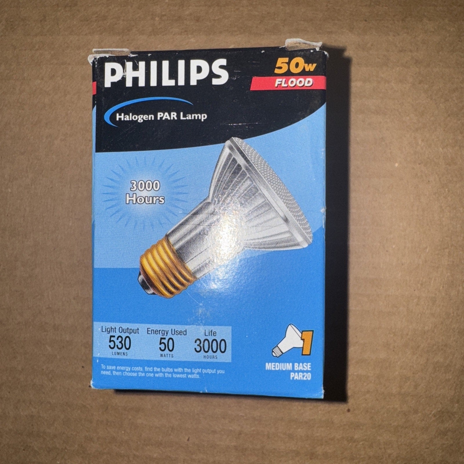Boxed Philips 50-watt halogen PAR flood lamp with medium base, highlighting 3000 hours lifespan, 530 lumens light output, and energy usage details on blue and black packaging.