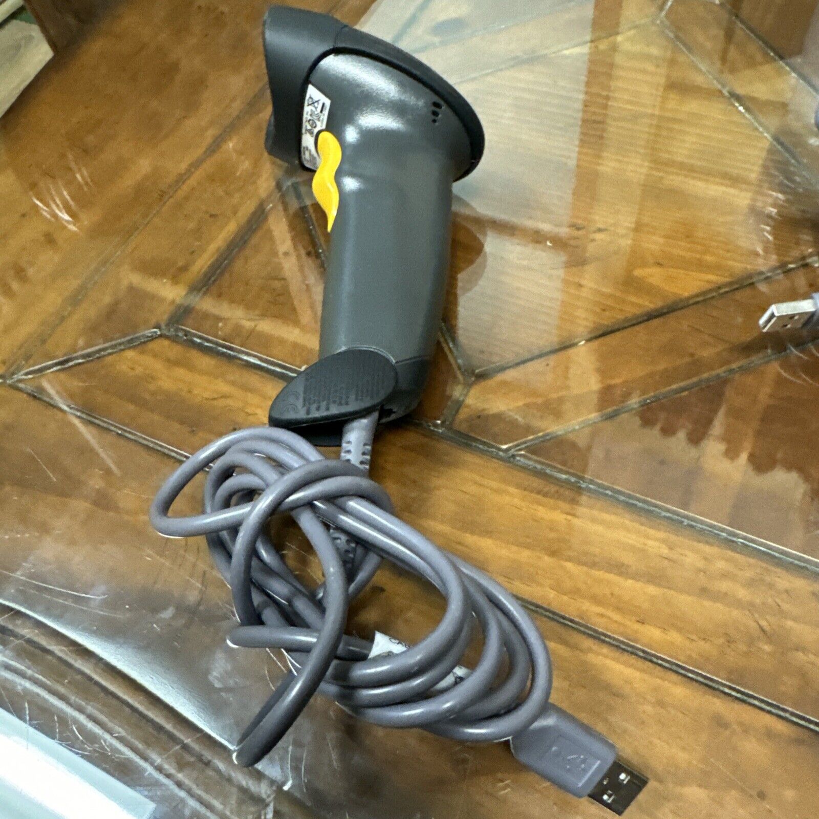 Symbol Motorola LS2208 handheld barcode scanner with USB cord for POS system on wooden glass table surface