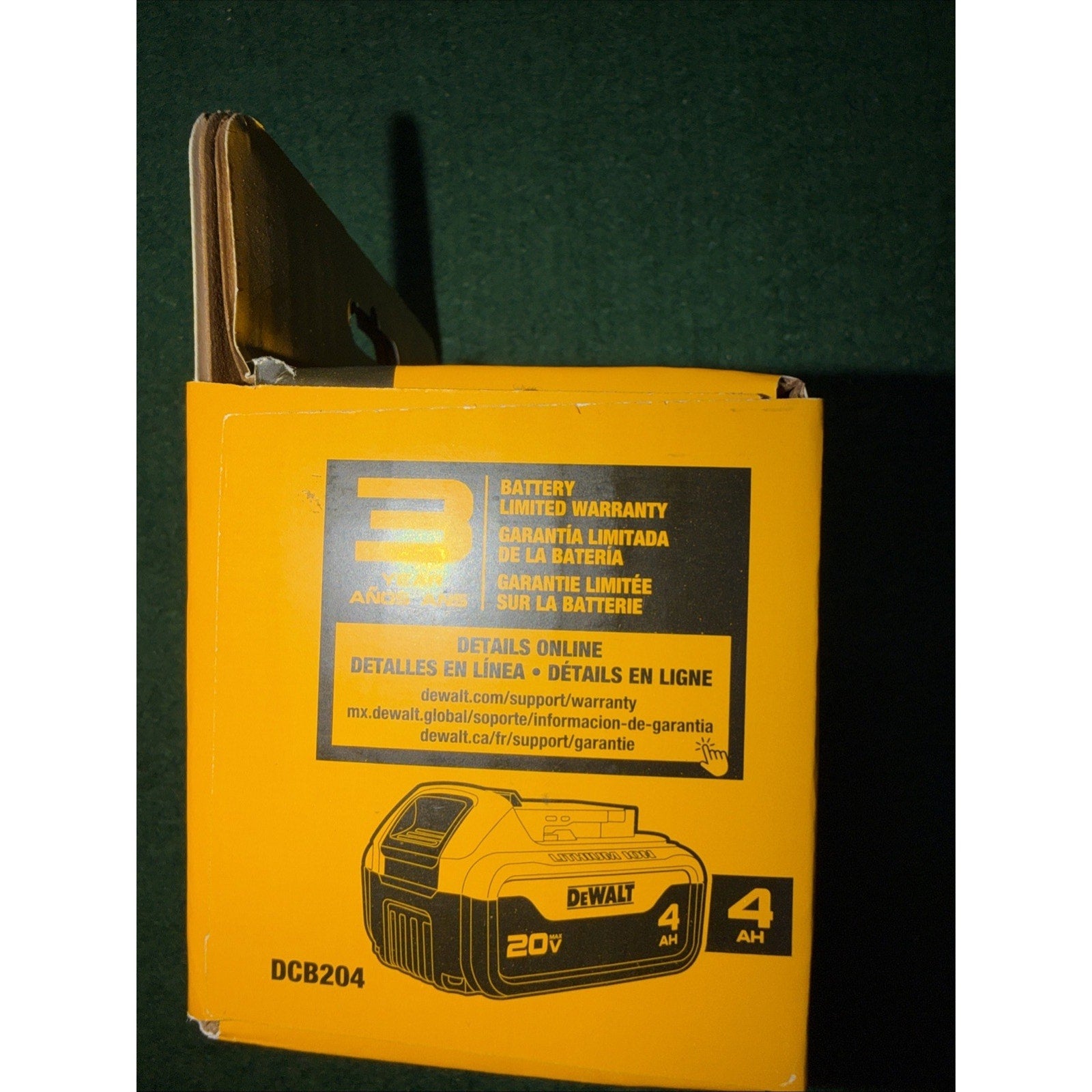 Yellow and black DeWalt battery packaging box showing a 20V 4Ah lithium-ion battery image, warranty details in English, Spanish, and French, and the model number DCB204.