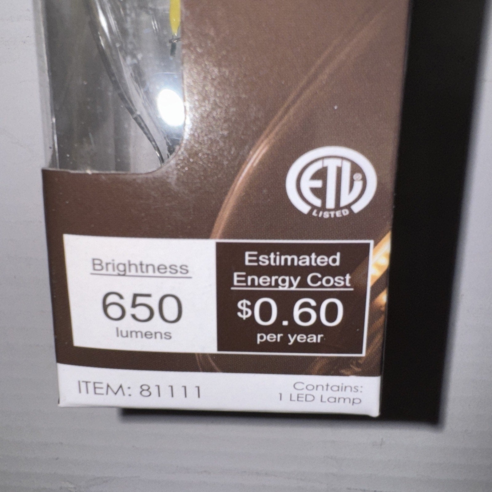 Close-up of Sunlite LED bulb packaging showing 650 lumens brightness and estimated $0.60 yearly energy cost