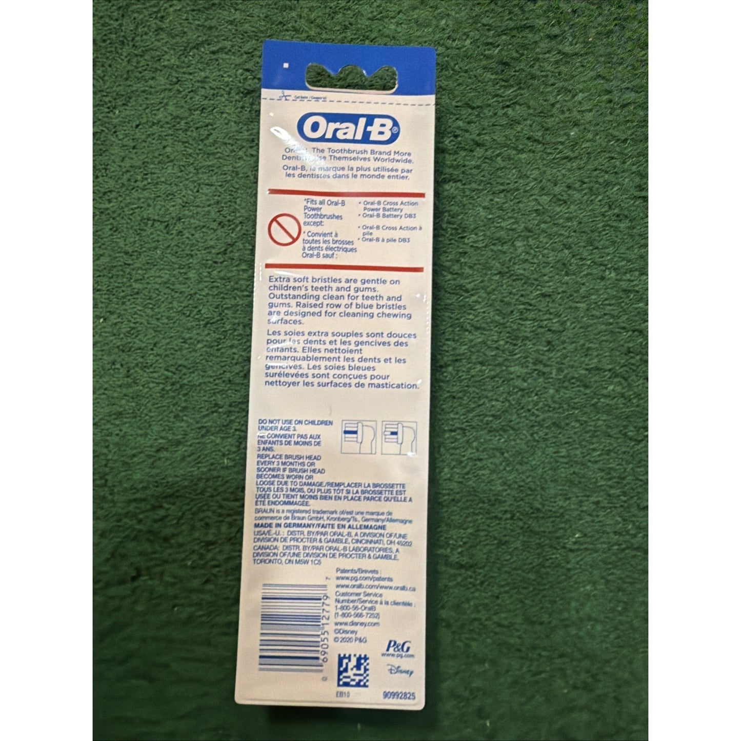 Back of an Oral-B toothbrush package displaying usage instructions, warnings about choking hazards for children, multilingual text, a barcode, and brand logos on a white and blue background.