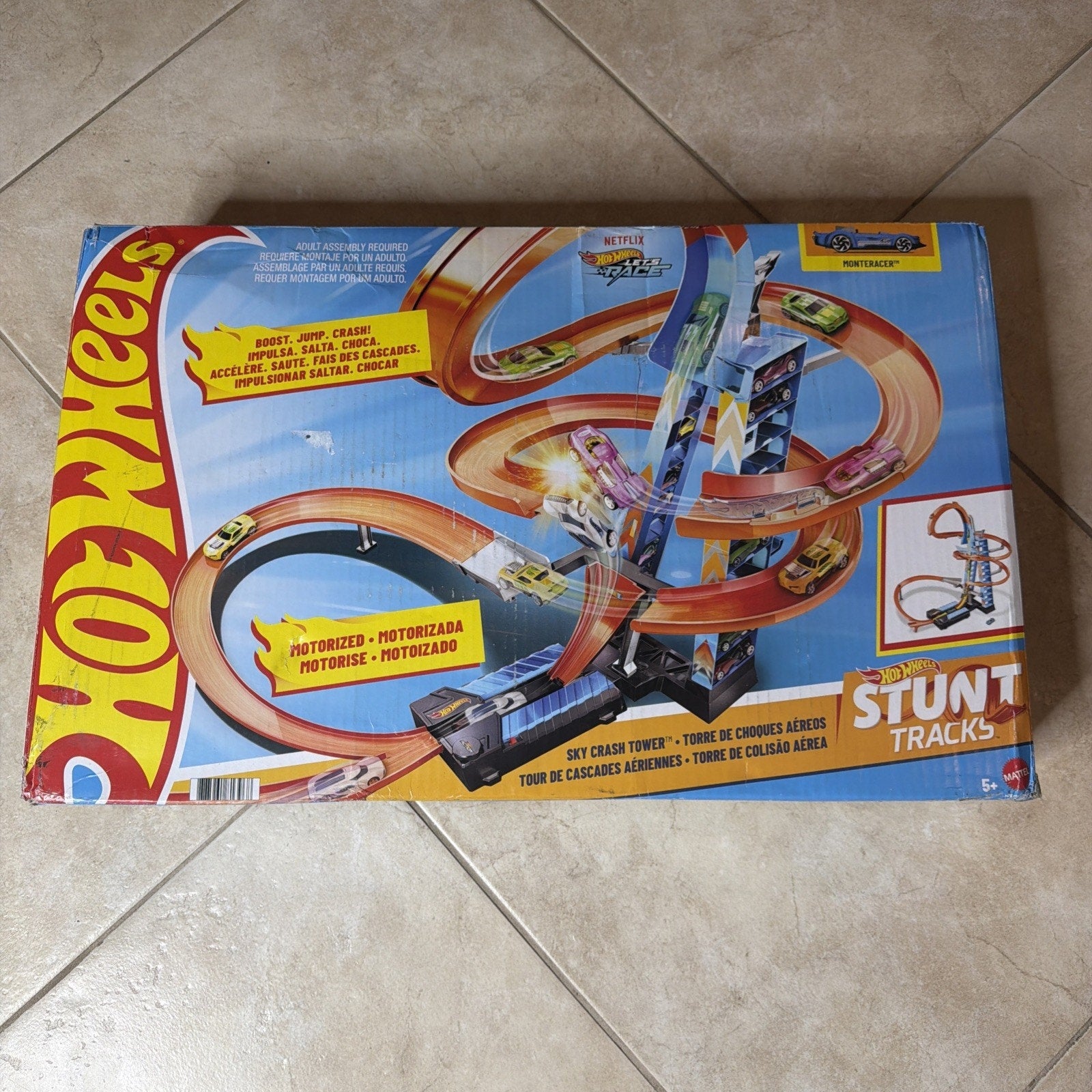 Rectangular box displaying a Hot Wheels Stunt Tracks playset with a motorized track featuring looping twists, jumps, and a tall spiral tower, designed for children ages 5 and up.