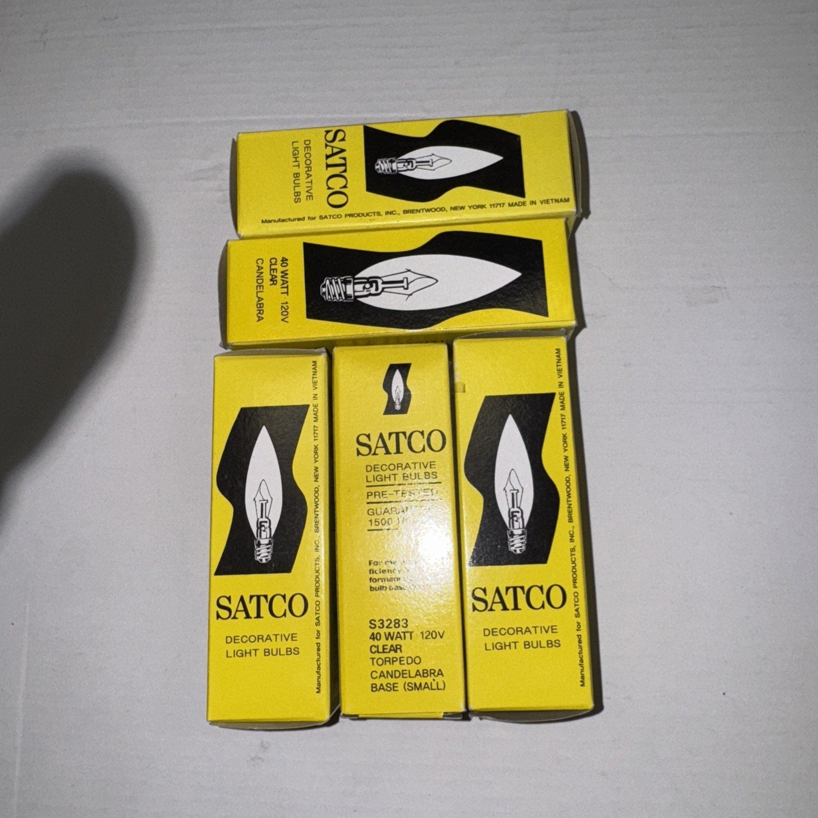 Five yellow SATCO S3283 40W 120V decorative clear torpedo light bulb boxes arranged on white surface