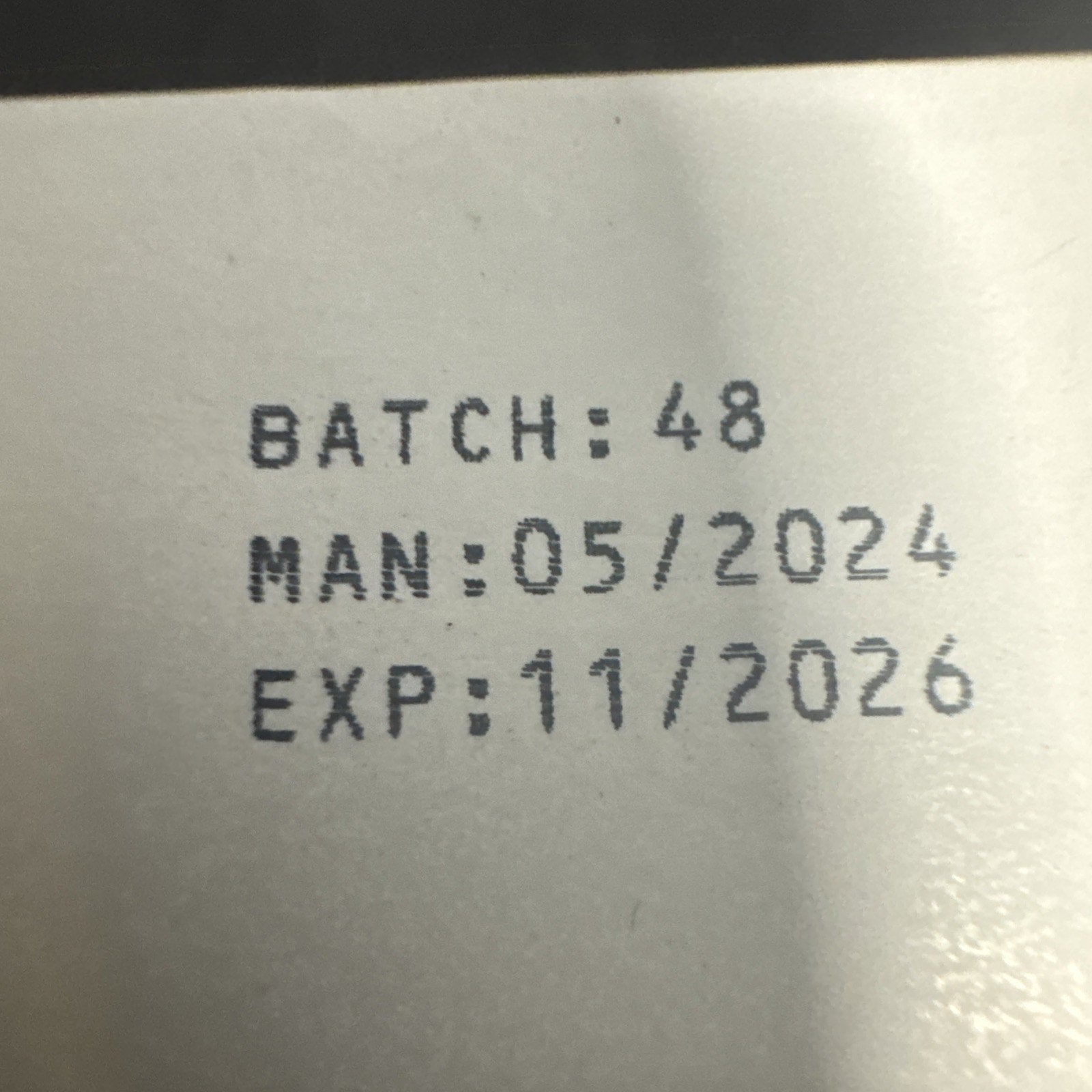 Close-up of product batch number 48 with manufacturing date 05/2024 and expiration date 11/2026 printed on packaging