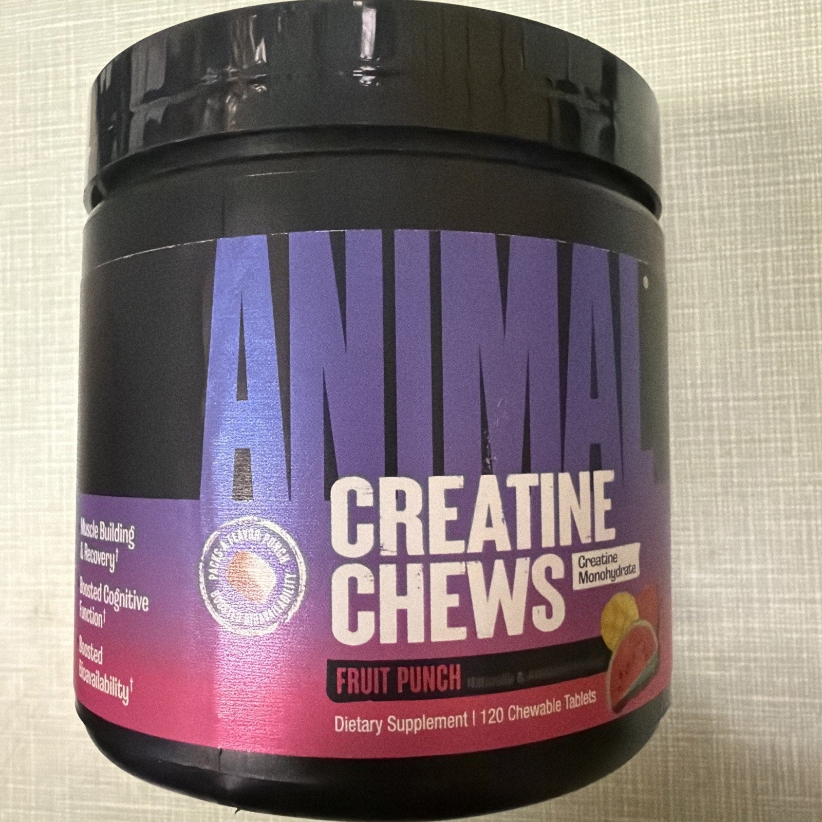 Black plastic container of Animal Creatine Chews dietary supplement in fruit punch flavor, featuring 120 chewable tablets and benefits like muscle building, cognitive function, and metabolism support.