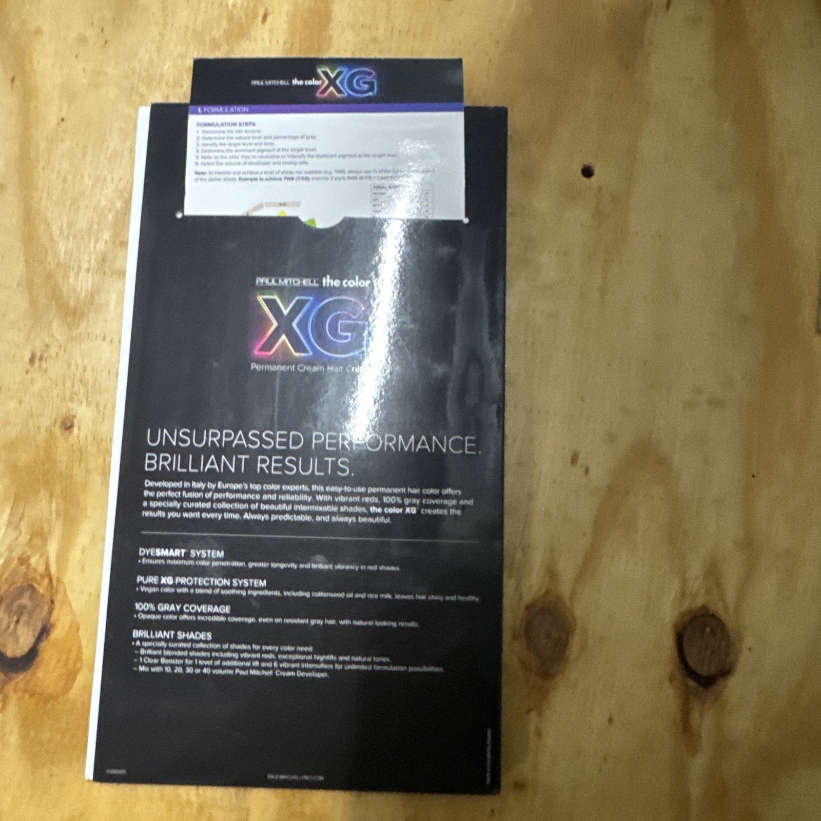 Paul Mitchell The Color XG swatch book showing permanent cream hair color samples and product details on black background